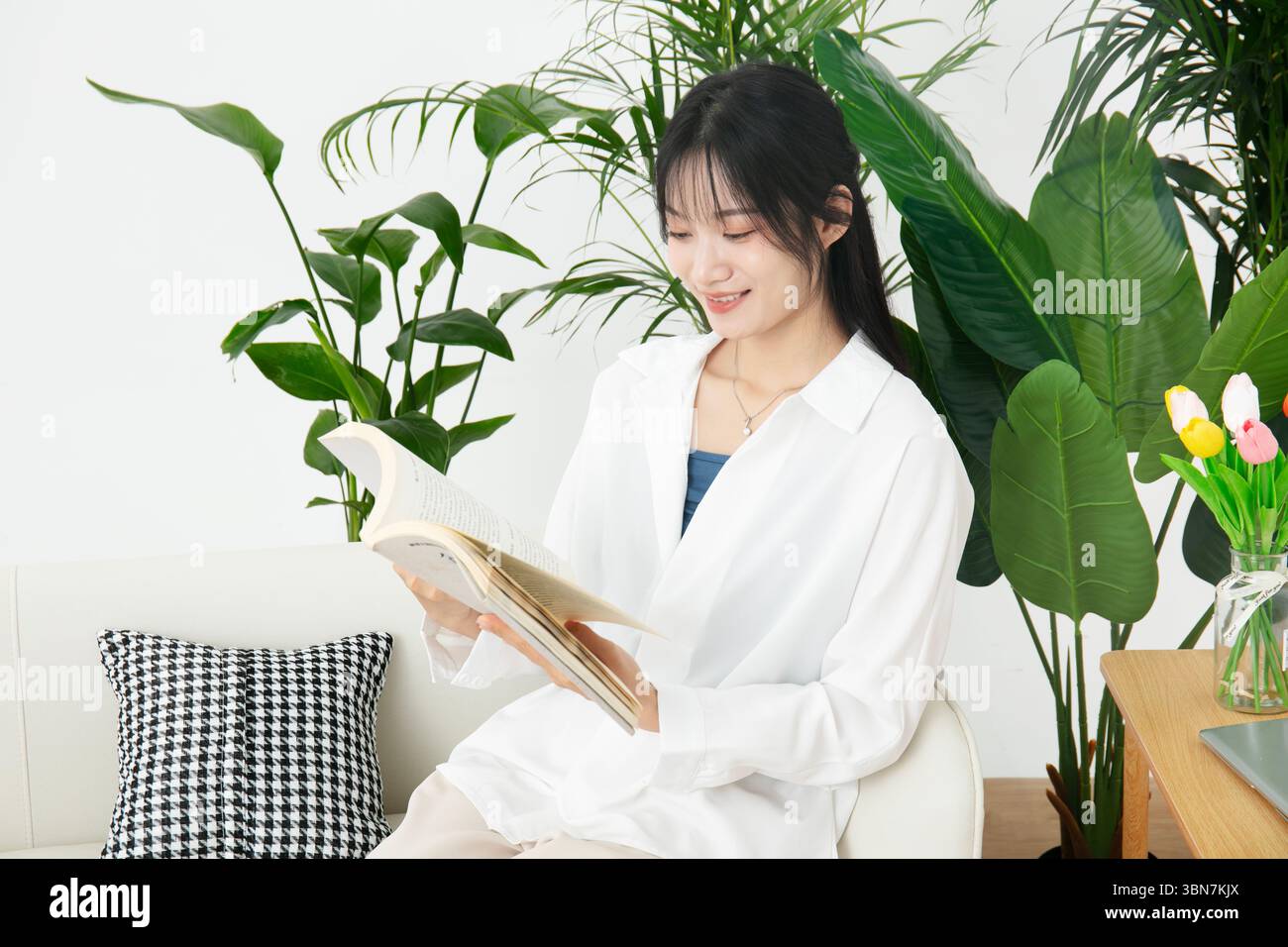 Una giovane donna che legge un libro sul divano Foto Stock