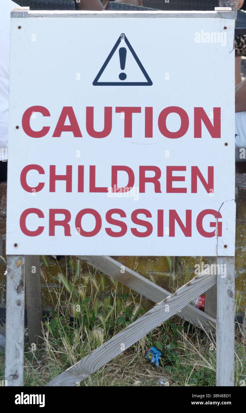 Un cartello con scritto attenzione i bambini che attraversano questo cartello si trovava fuori da un pub britannico Foto Stock