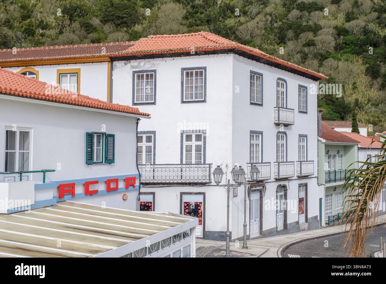 Edifici coloniali portoghesi tradizionali con tetti in terracotta e balconi in ferro nella strada del villaggio dell'Azorean. Facciate bianche, persiane colorate, pender Foto Stock