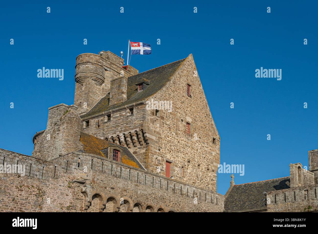 Il municipio di Saint-Malo si vede dall'interno della città murata, mostrando la sua architettura medievale in pietra sotto un cielo azzurro. Foto Stock