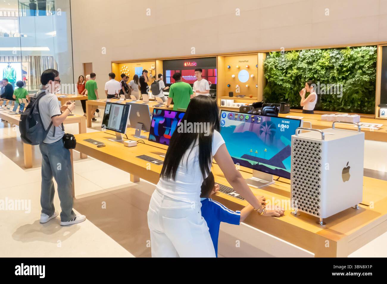 Le persone stanno navigando nell'elettronica dei computer Apple iMac Pro in un negozio Apple illuminato. Centro commerciale Iconsiam, Bangkok Thailandia Foto Stock