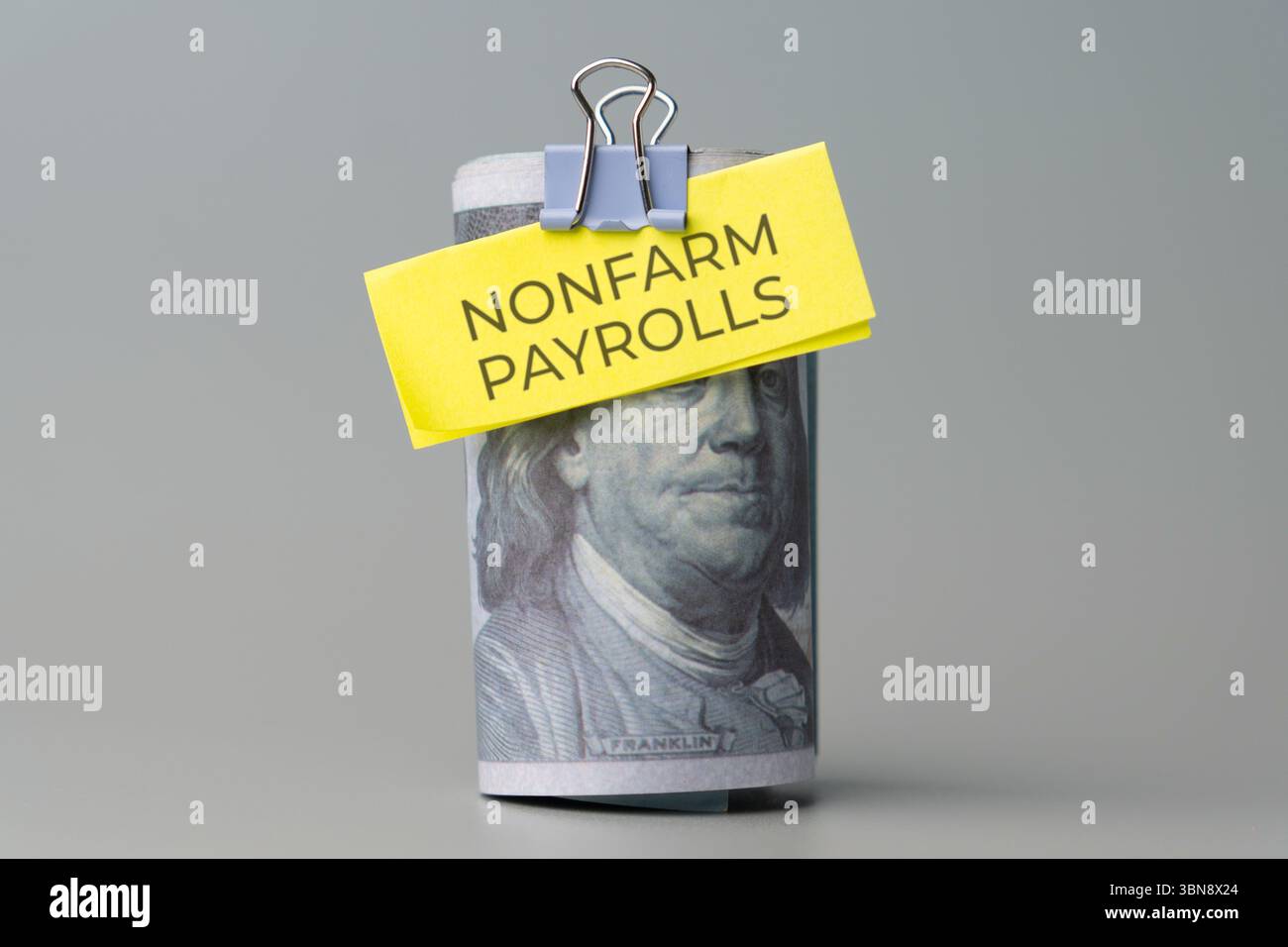 Una pila di banconote da cento dollari con una nota "NONFARM PAYROLL" allegata. Indicatore economico, dati sul mercato del lavoro, statistiche sull'occupazione Foto Stock