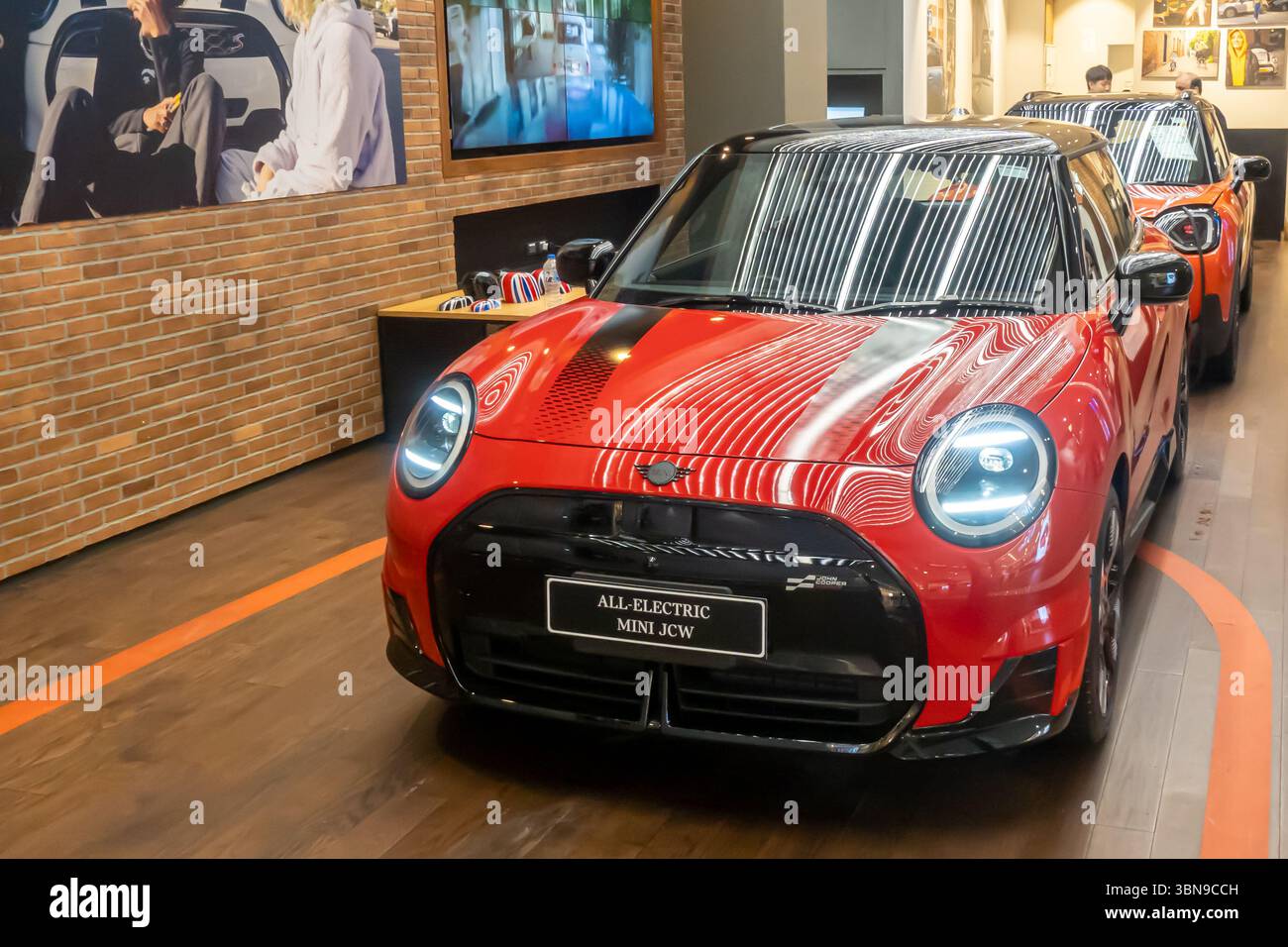Mini JCW rossa con capote con la targhetta "All Electric Mini JCW" in uno showroom Foto Stock