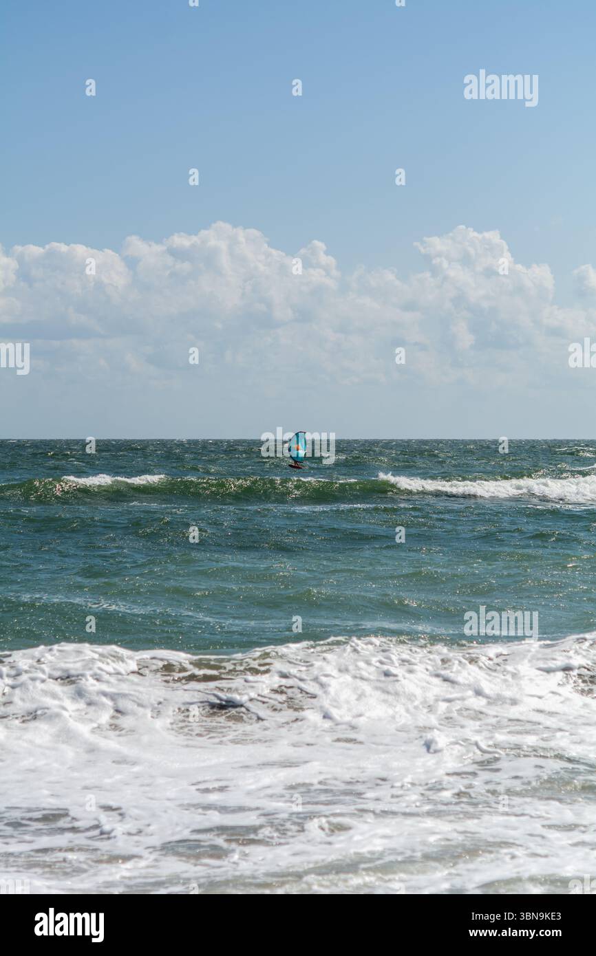 Windsurfer sul Mar Nero in Romania. Un windsurf che vola attraverso il Mar Nero sotto un cielo parzialmente nuvoloso. Foto Stock