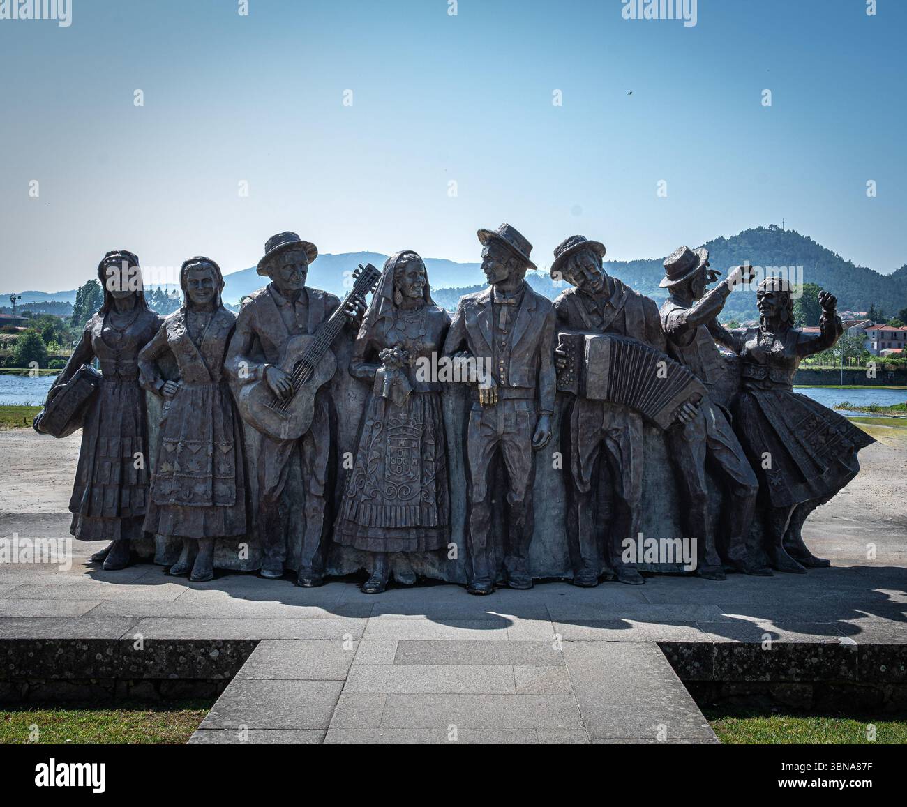 Statue in bronzo di danzatori tradizionali portoghesi sulla riva del fiume Lima nell'antica città di Ponte de Lima, Portogallo. Foto Stock