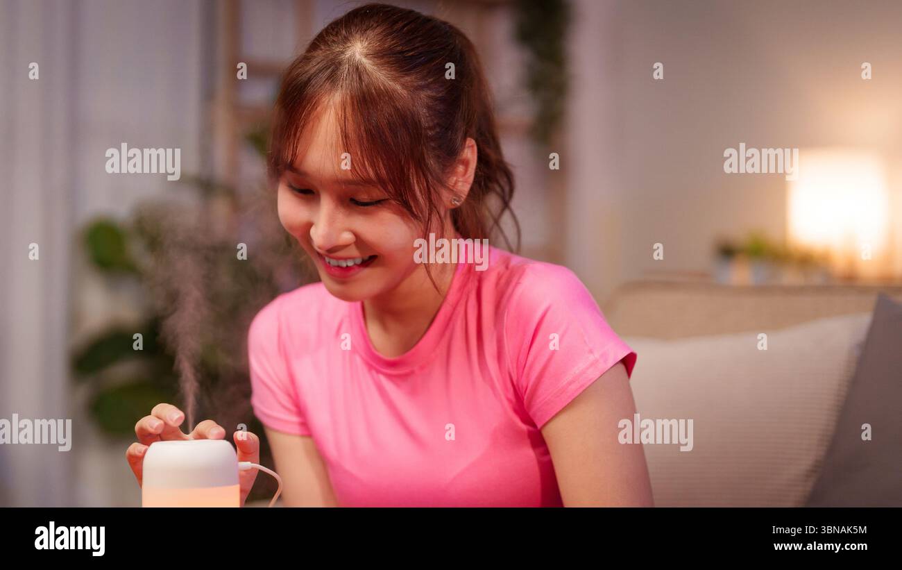 La donna asiatica adulta gode del diffusore di aromaterapia come un modo per rilassarsi e promuovere il benessere. L'aromaterapia aiuta a migliorare la concentrazione migliorare il sonno e aumentare l'umore Foto Stock