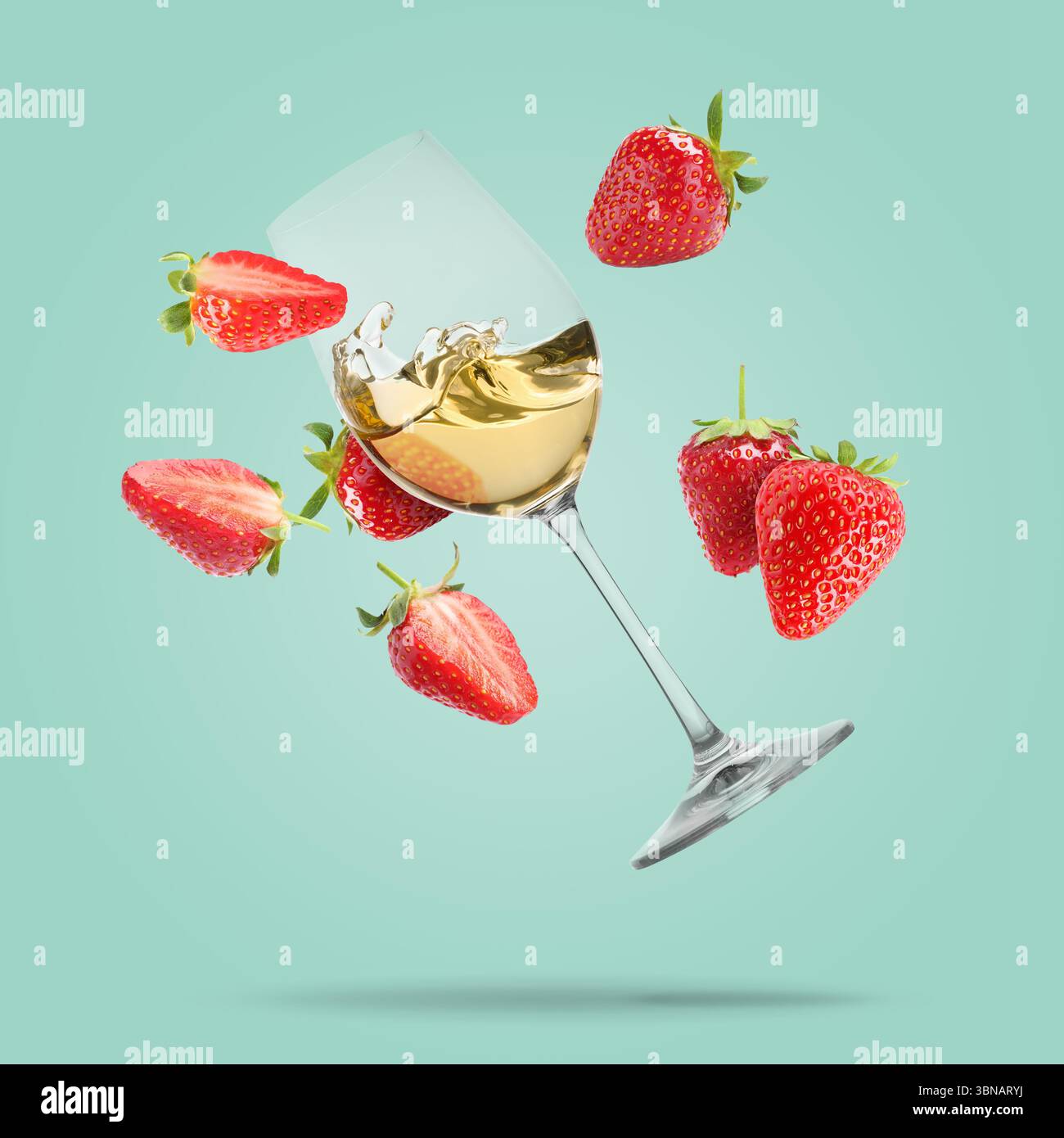 Vino in bicchiere e fragole fresche che cadono su sfondo turchese pastello Foto Stock