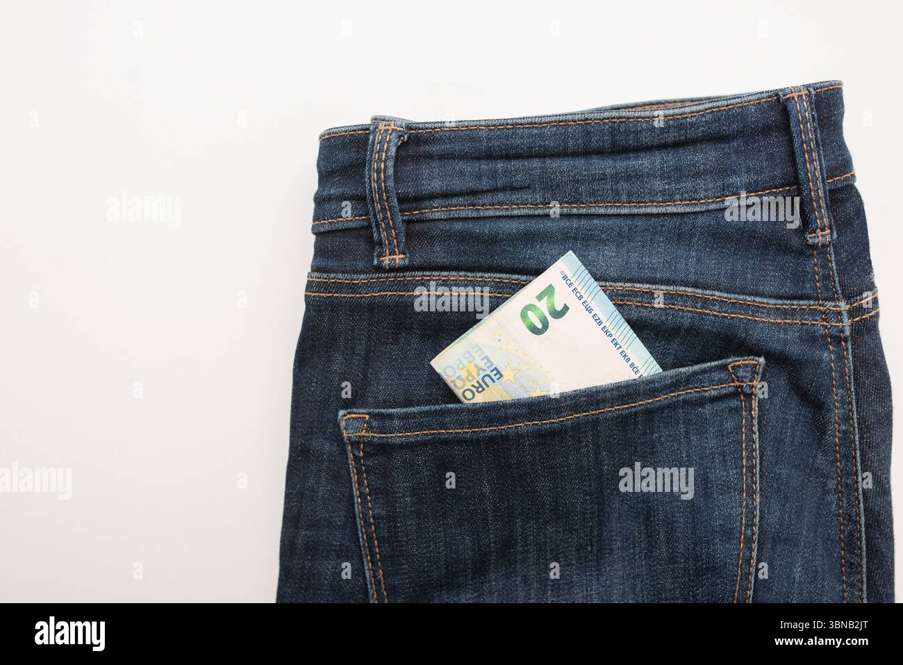 I jeans in denim scuro presentano una banconota da venti euro che sbircia dalla tasca posteriore, illustrando lo stile casual e il concetto di gestione del denaro nella giornata Foto Stock
