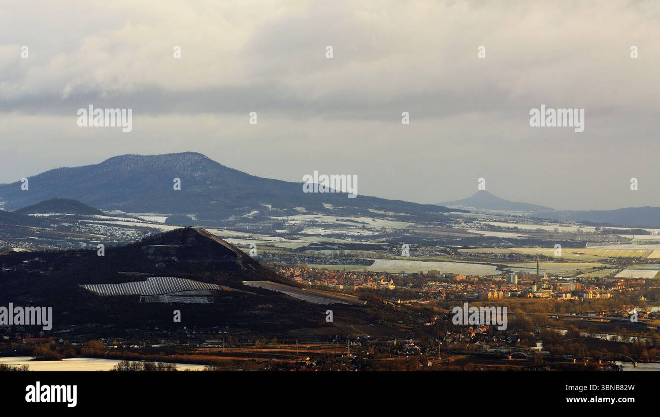 Paesaggio collinare ceco con edifici della città e polvere di neve alla luce del mattino Foto Stock