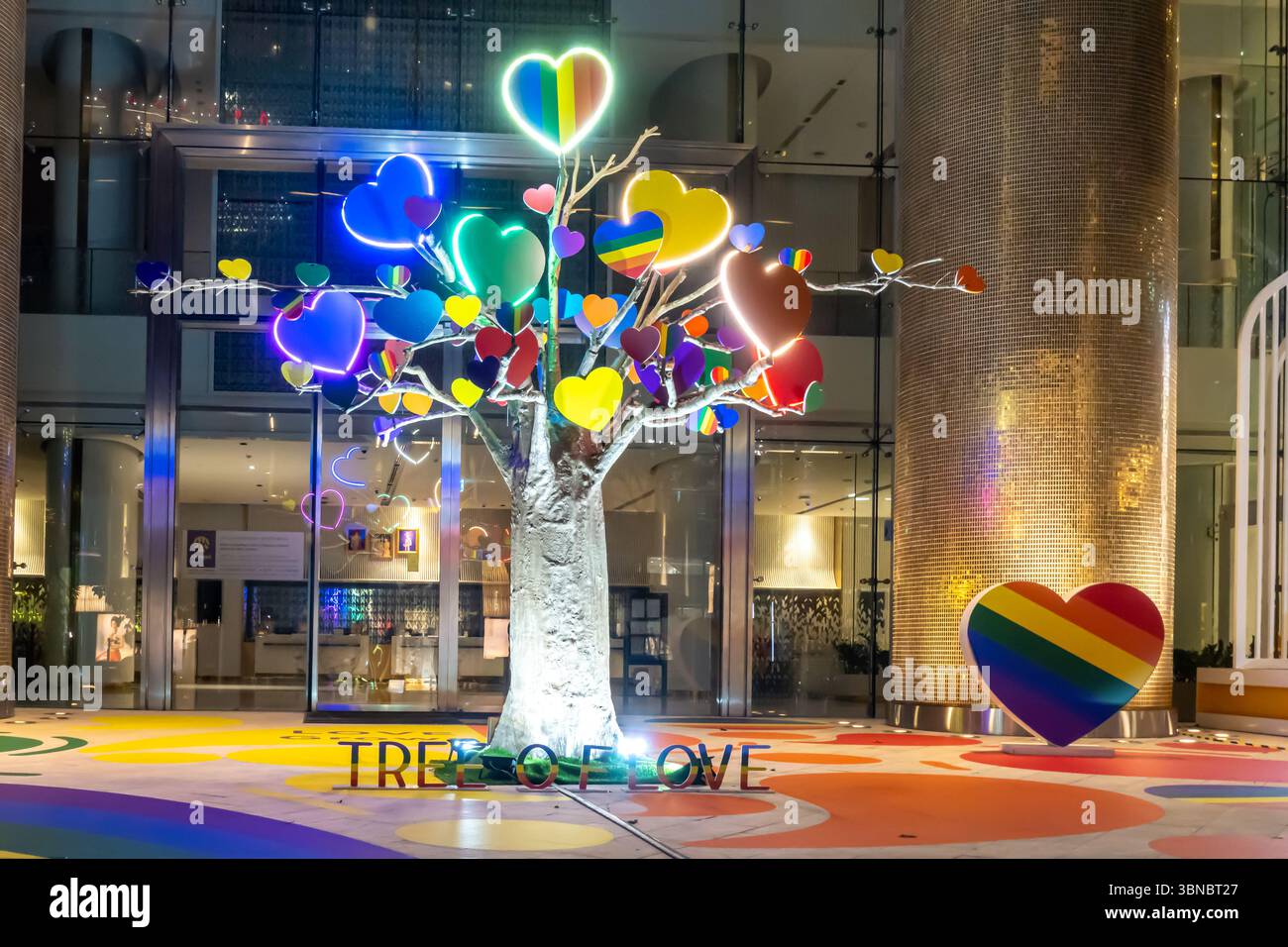 Scultura dell'albero dell'amore adornata da cuori colorati, con un grande cuore che mostra i colori LGBTQ+ Pride, Siam Paragon, Bangkok, Thailandia Foto Stock
