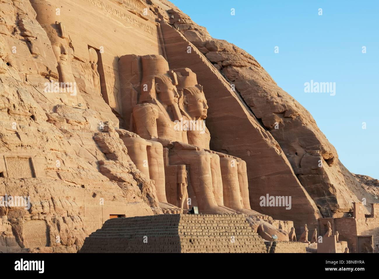 Vista laterale del Tempio di Abu Simbel all'alba, con la sua enorme facciata in pietra arenaria e le colossali statue del faraone Ramsete II Foto Stock