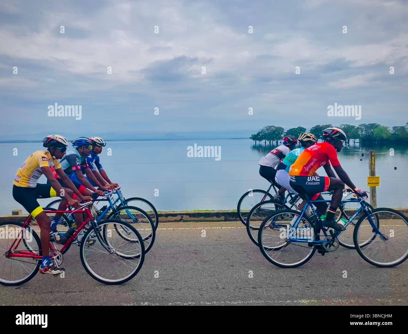 Ciclisti che percorrono il panoramico lungomare, abbracciando la perfetta miscela di sport e natura Foto Stock