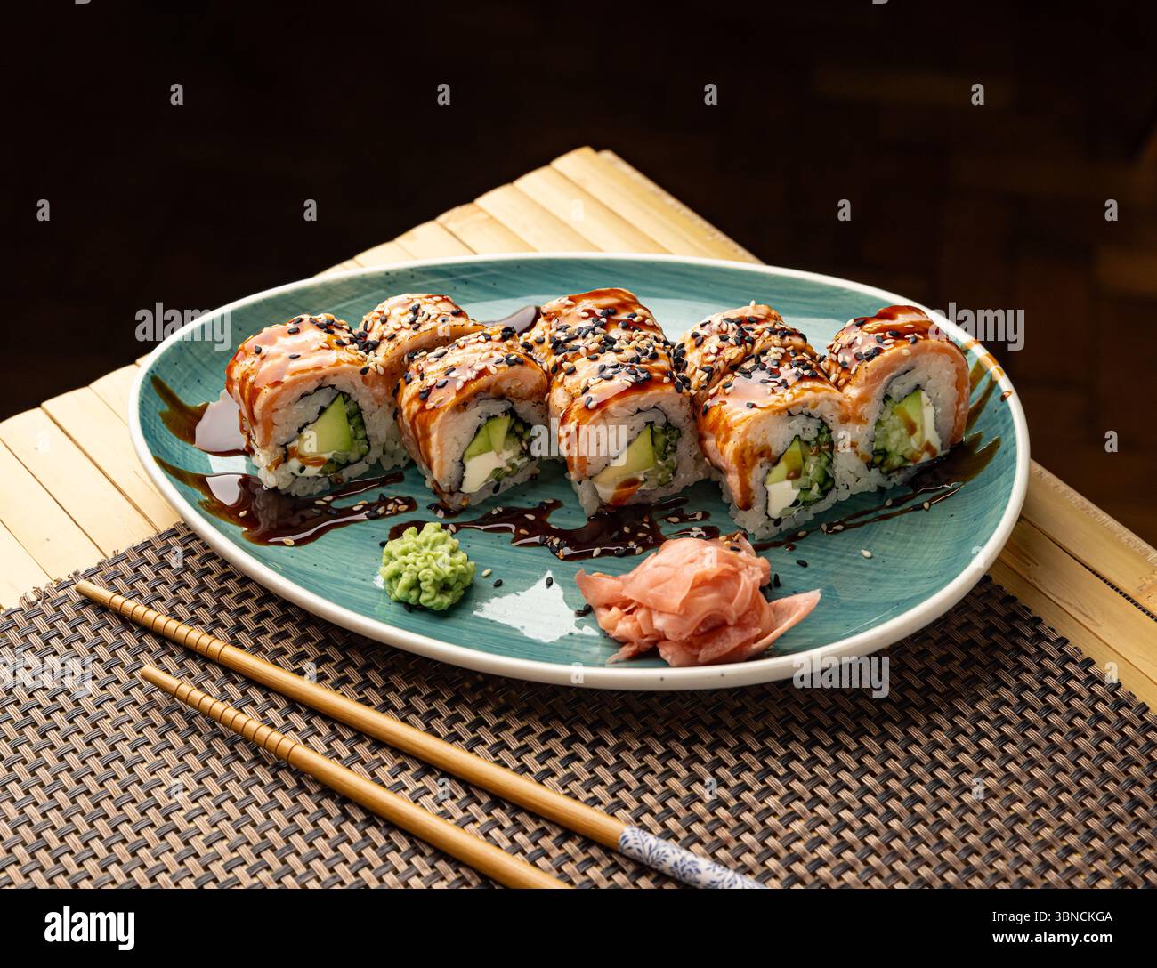 Deliziosi sushi con salmone, avocado, formaggio spalmabile, semi di sesamo e salsa di soia su un piatto Foto Stock