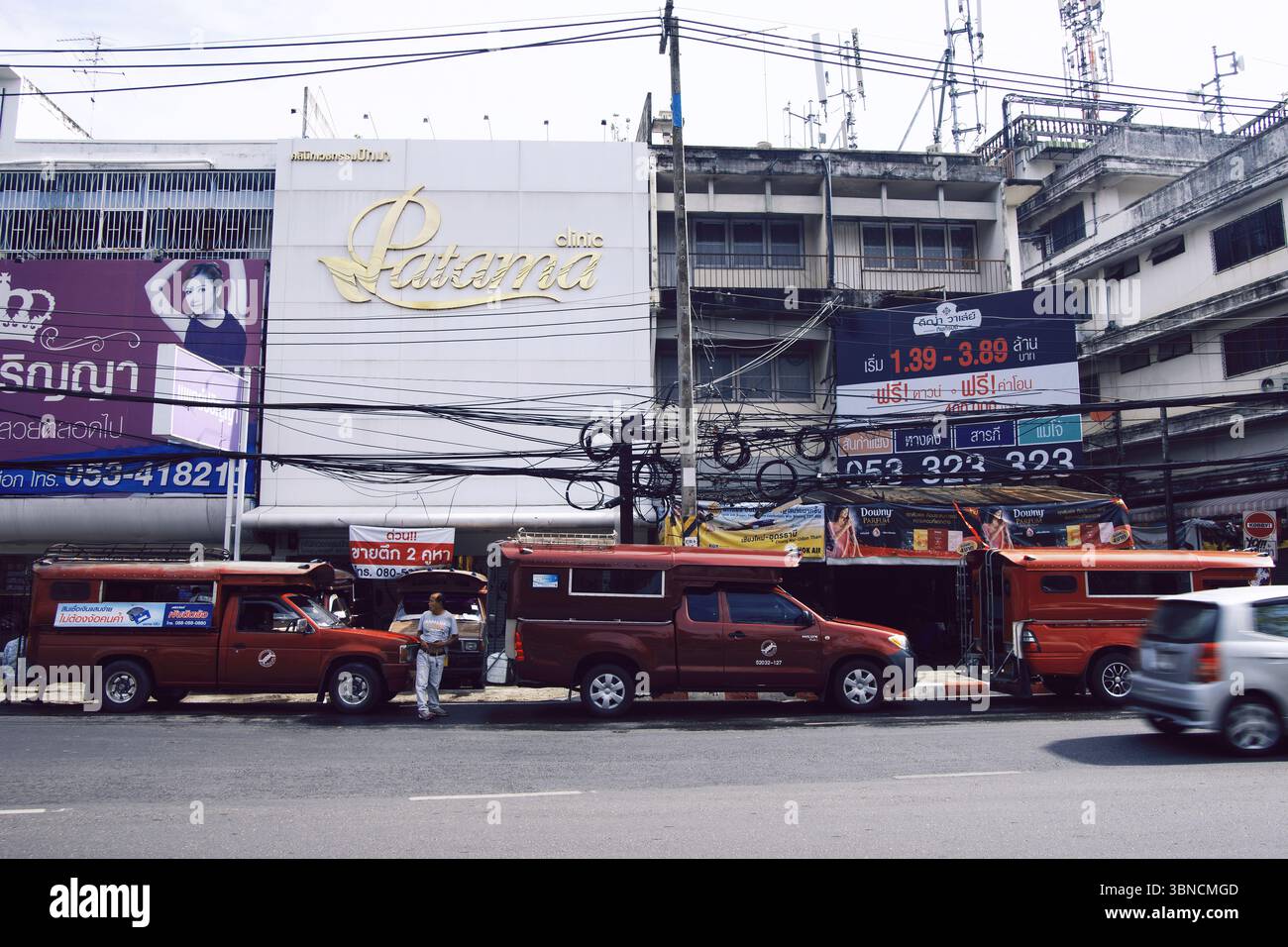 Songthaew Red Trucks e Tangled Power Lines in Chiang mai Street, Thailandia Foto Stock