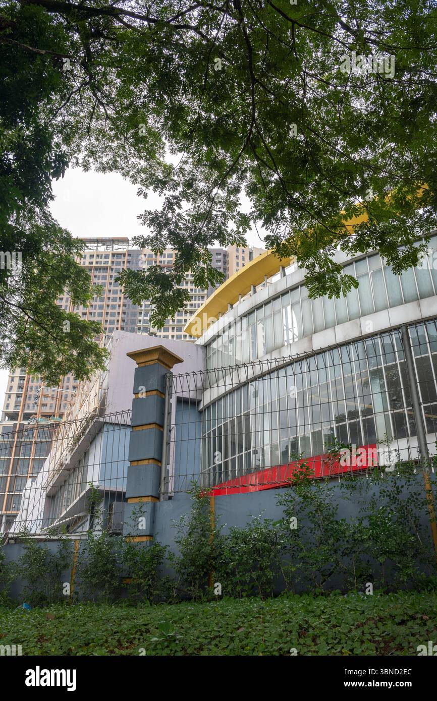 Grande edificio con un tetto rosso e un tetto giallo. L'edificio è circondato da alberi. Gli alberi sono verdi e le foglie sono grandi Foto Stock