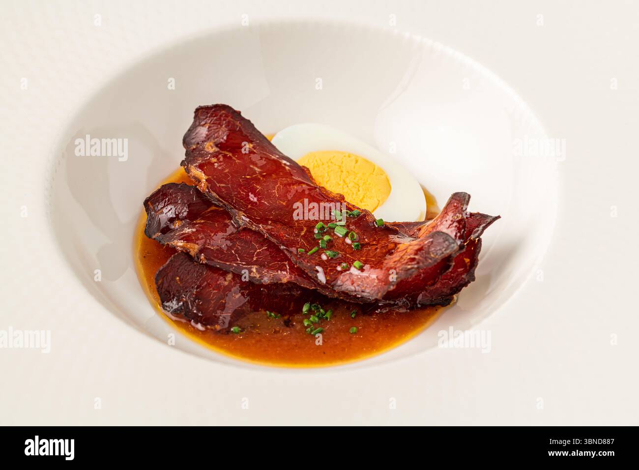 Barbecue a fette di maiale con uovo sodo in una salata salsa marrone Foto Stock