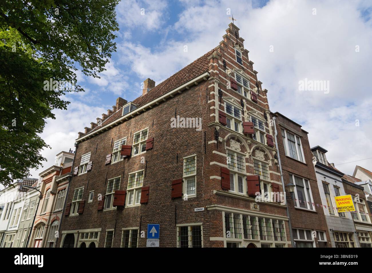 Storico edificio in mattoni con tettoie a gradini e persiane rosse a Gorinchem, Paesi Bassi, che mostra la tradizionale architettura olandese. Gorinchem, Paesi Bassi Foto Stock