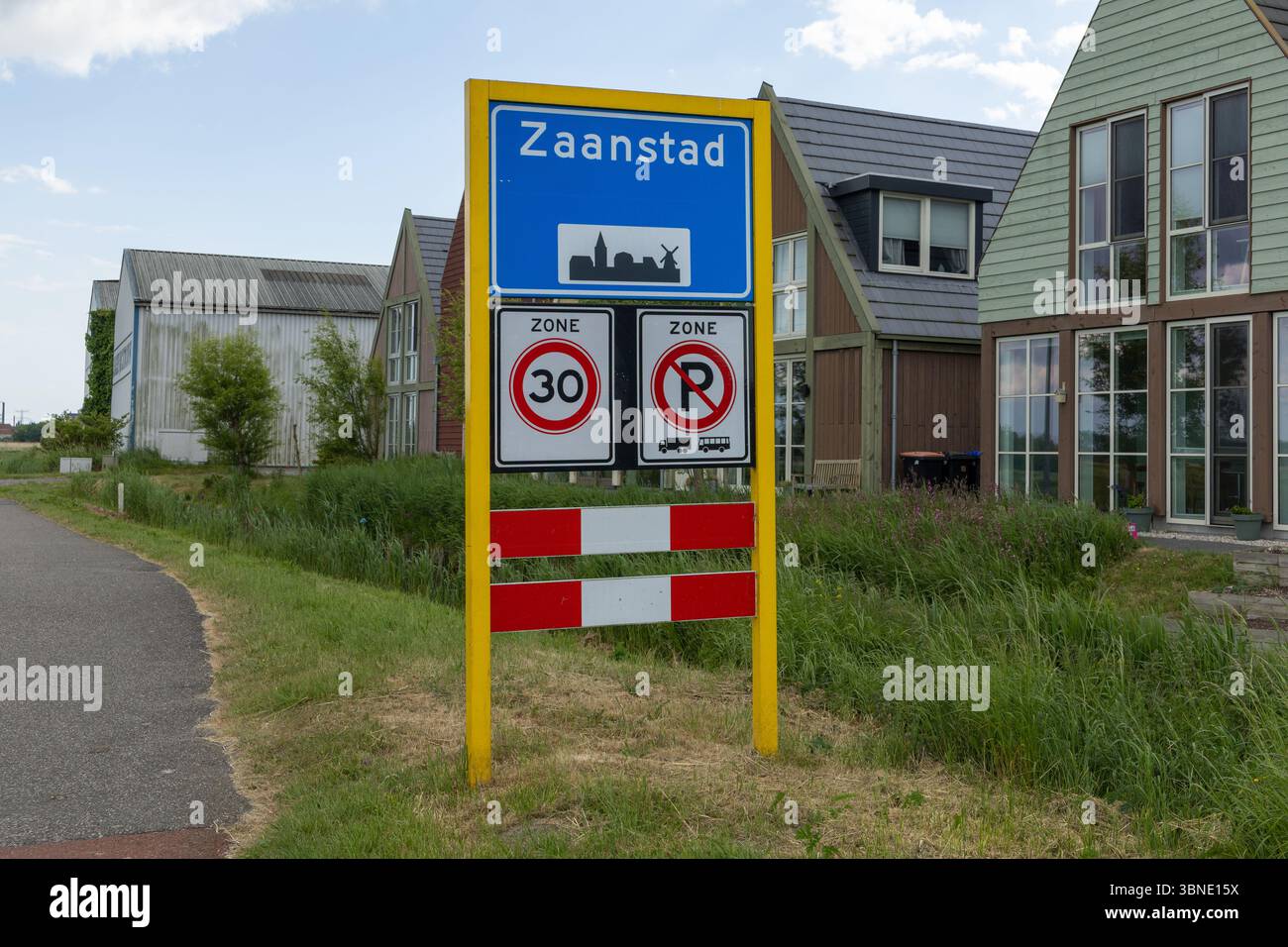 Questa foto vivace mostra un cartello con i limiti della città di Zaanstad con un'icona distintiva del mulino a vento, accanto a una zona di velocità di 30 km/h e a un parcheggio limitato, perfetto Foto Stock