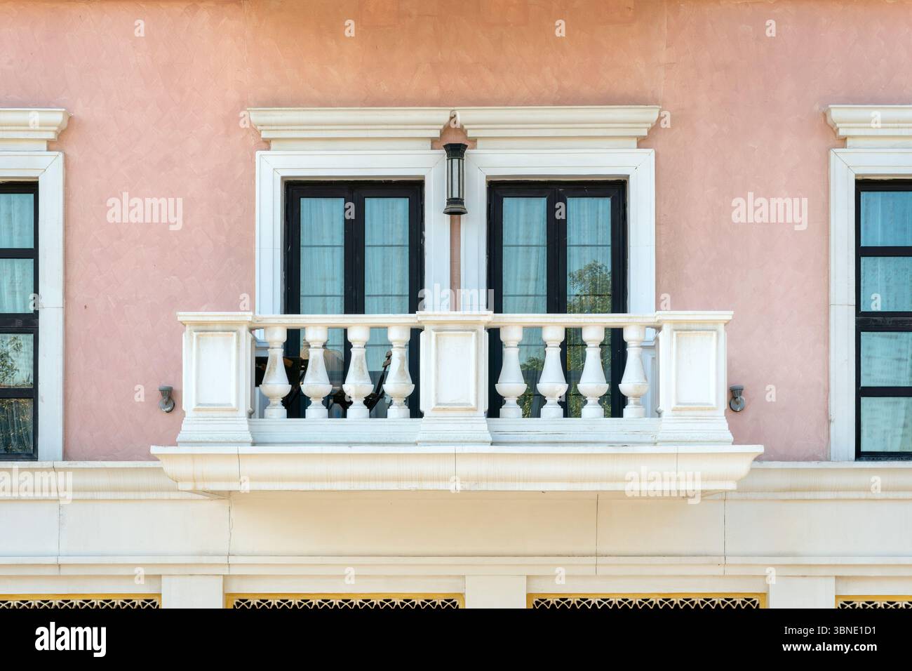 Esterno di un vecchio edificio residenziale di colore rosa con finestre di vetro e splendidi balconi bianchi Foto Stock