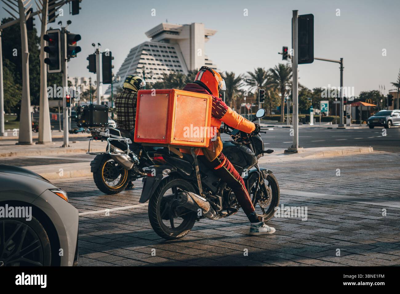 Un corriere di consegna del cibo sta guidando un ordine a casa di un cliente su un ciclomotore. cibo da asporto durante la quarantena. trasporto consegna pacchi a domicilio. m Foto Stock
