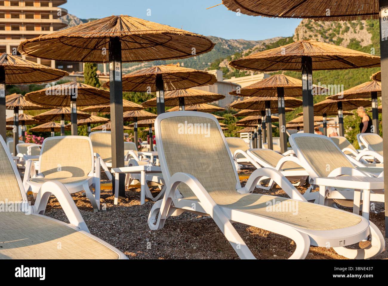 Bar, Montenegro, 23 giugno 2025, spiaggia attrezzata di ciottoli sul mare Adriatico, lettini vuoti al tramonto Foto Stock