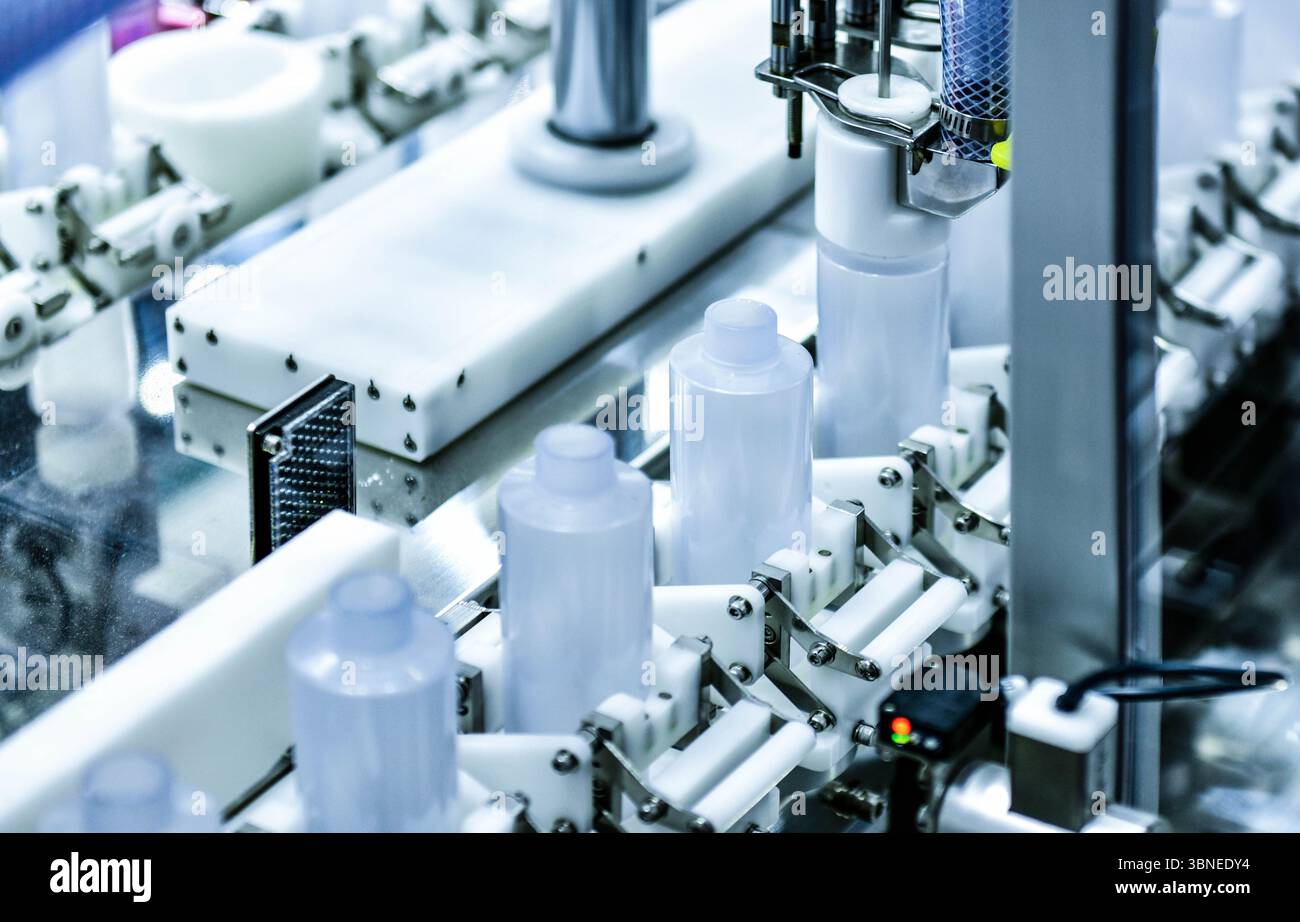 Bottiglie di plastica bianche in un nastro trasportatore su una macchina di riempimento verticale automatica di alta qualità. nella linea di produzione della fabbrica Foto Stock