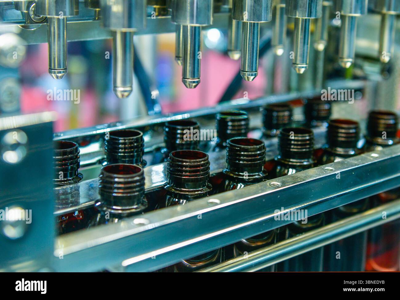 Bottiglie di vetro in un nastro trasportatore su una macchina di riempimento verticale automatica di alta qualità. Nella linea di produzione della fabbrica Foto Stock