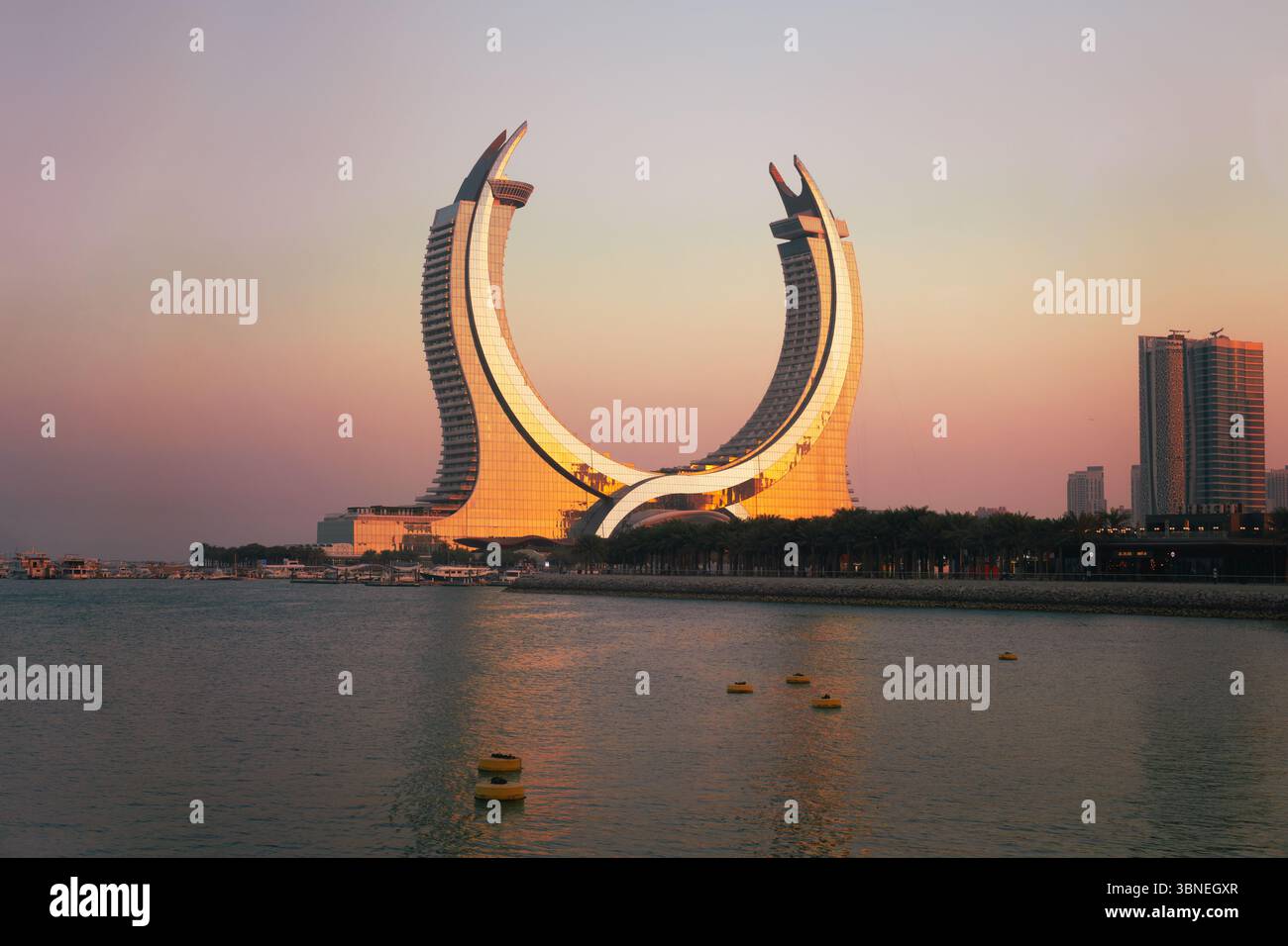 Doha, città di Lusail, Qatar - 1° febbraio 2025: Torre a mezzaluna dall'isola di al Maha in Qatar, con un cielo dai colori vivaci prima del tramonto Foto Stock