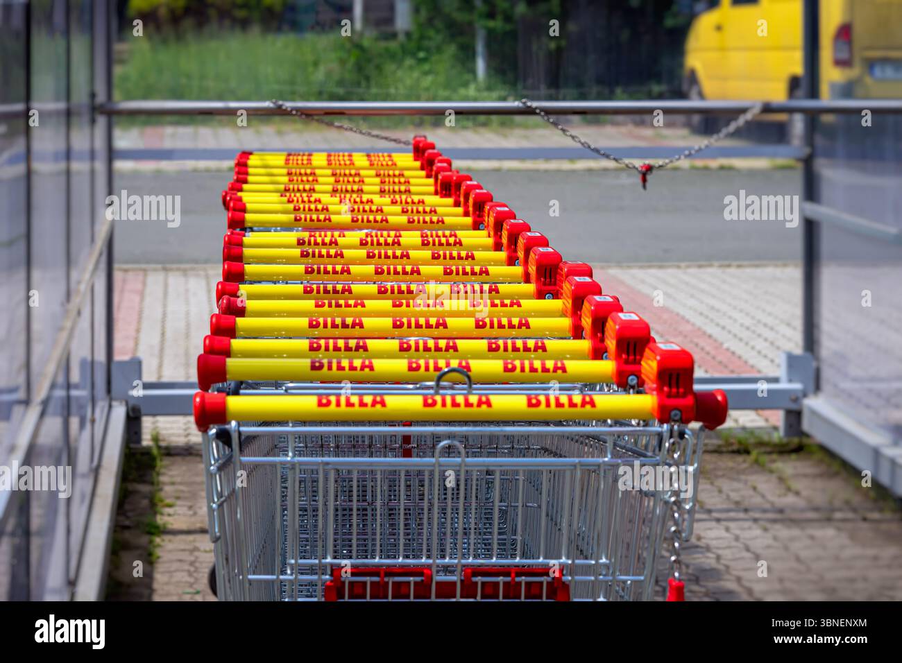 Carrelli Billa in fila. Carrelli della spesa Billa ordinatamente disposti con audaci marchi gialli e rossi vicino all'ingresso del negozio. Concetto di retail, branding Foto Stock