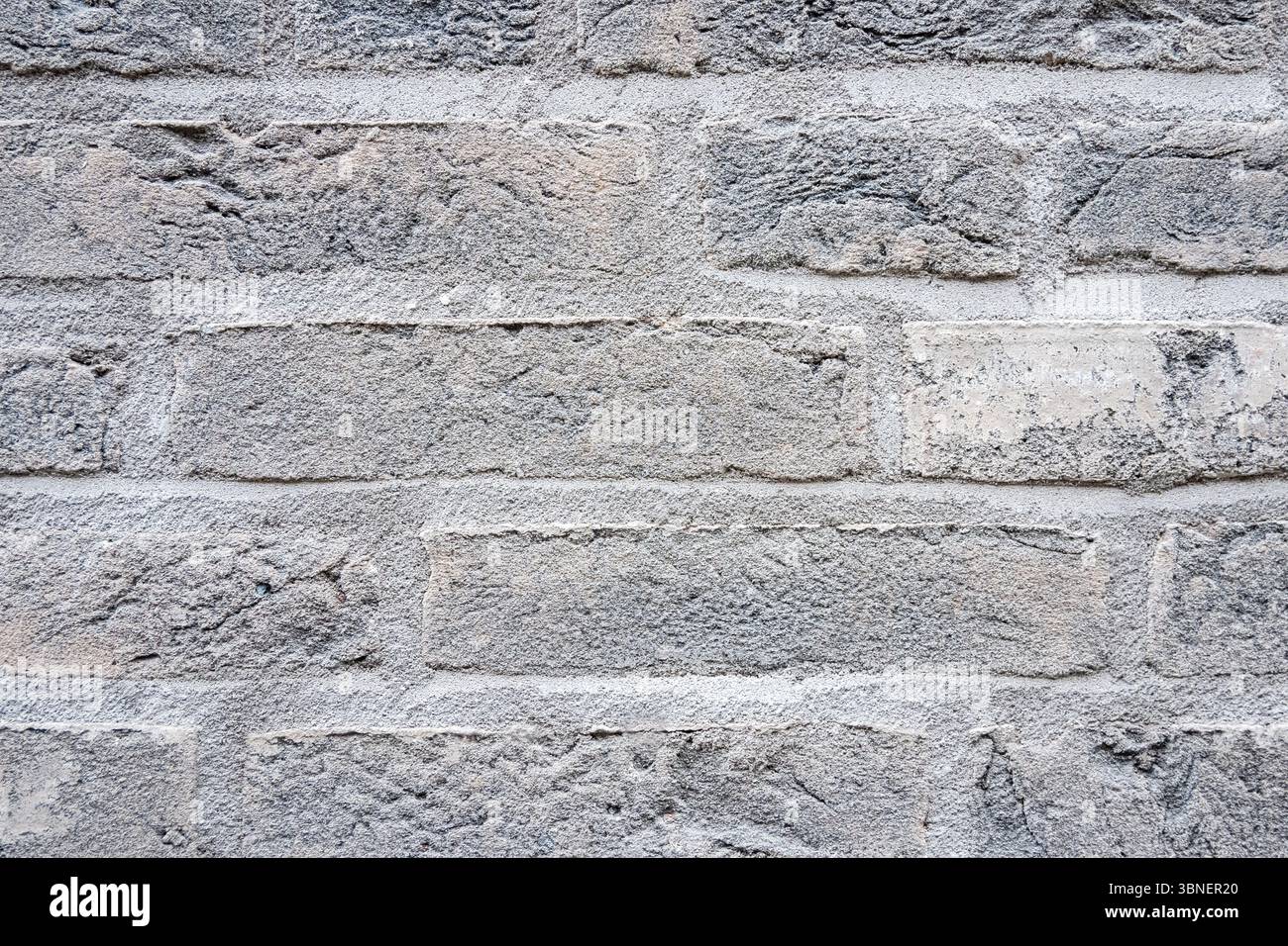 Il muro di pietra strutturale grigio dell'antico edificio è costituito da mattoni. Natura sfondo strutturale. Foto Stock