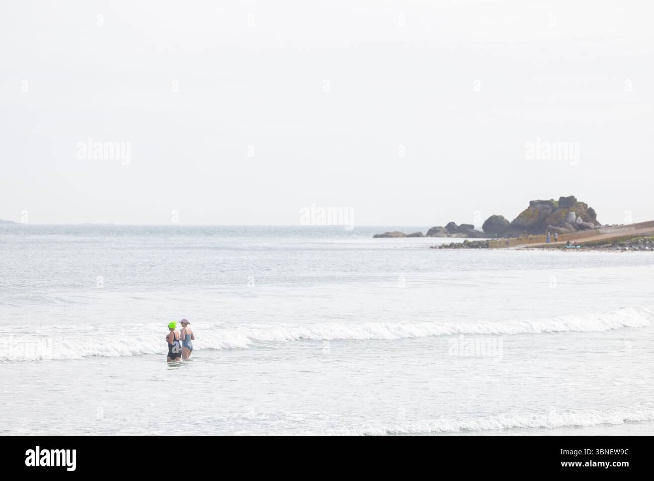 Surfisti e nuotatori sulla spiaggia di Carnlough on the Co Antrim Coast, Irlanda del Nord. Uno dei percorsi costieri più belli d'Irlanda. Foto Stock