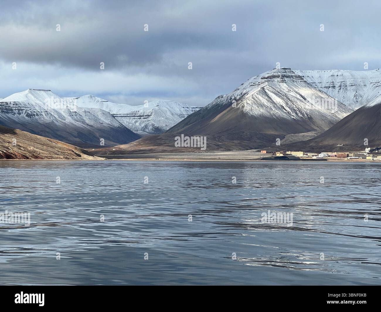 Le montagne innevate si riflettono nelle tranquille acque di un fiordo fuori dall'insediamento di Pyramiden, Spitsbergen, Svalbard - Immagine stock catturata con smartphone