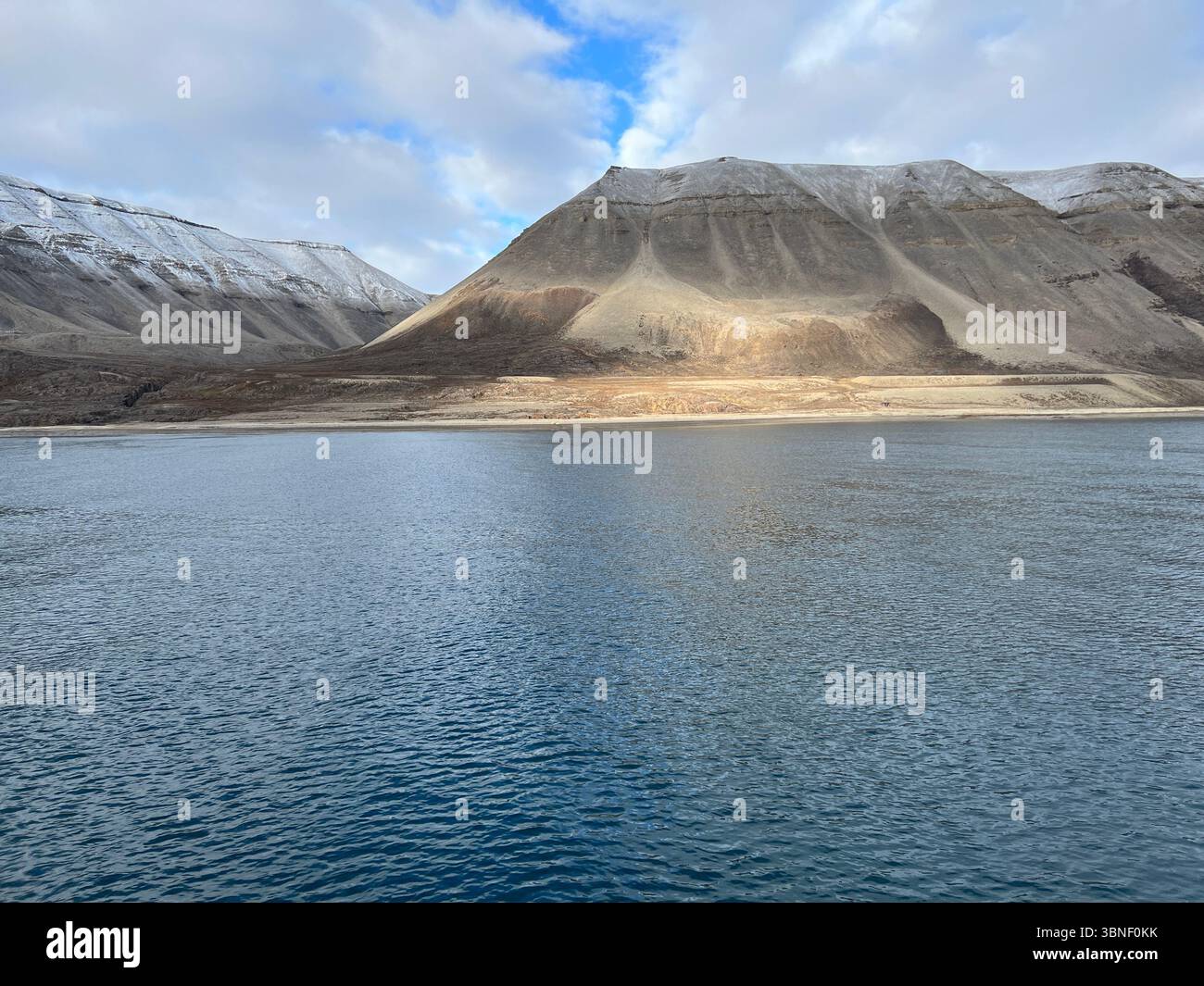 Maestose montagne innevate si riflettono nelle tranquille acque di un fiordo. Longyearbyen, Svalbard - Immagine stock catturata con smartphone