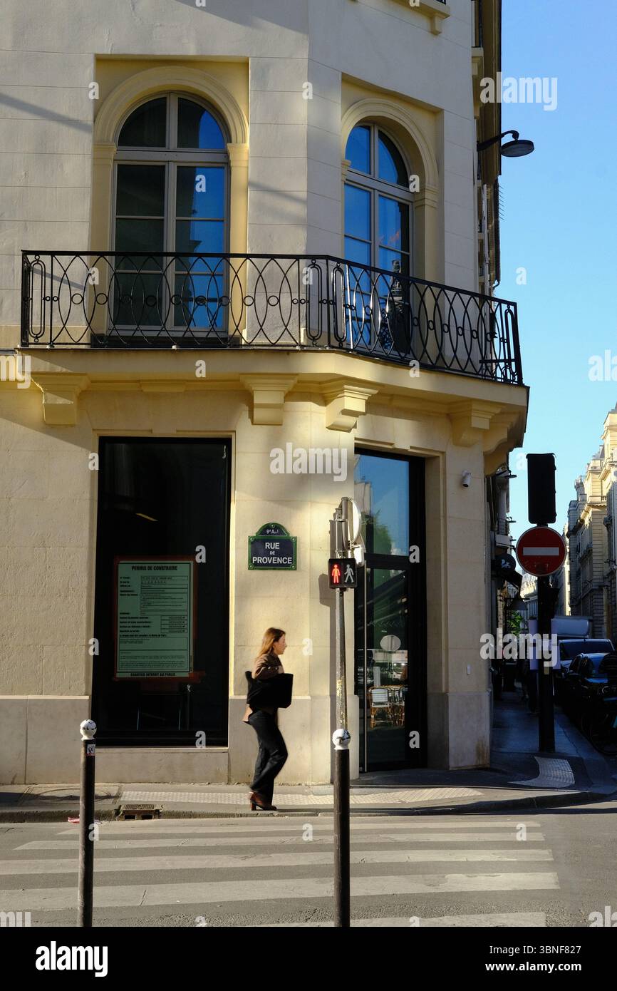 Persone che esplorano le strade di Parigi al sole dell'ora d'oro con la tipica architettura parigina sullo sfondo Foto Stock