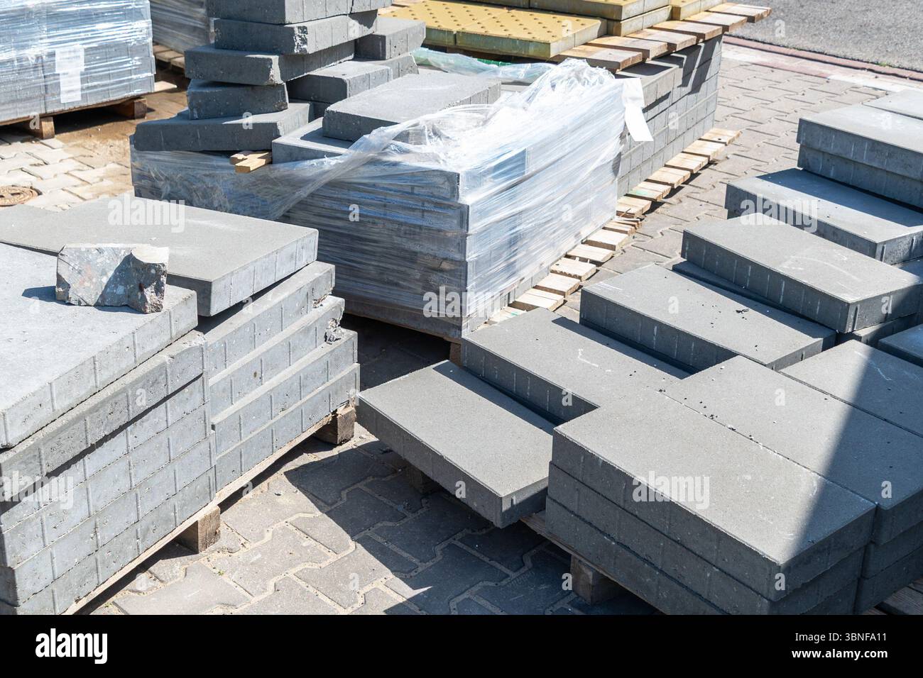 Lastre di pavimentazione in calcestruzzo grigie impilate su pallet in legno all'aperto. Foto Stock
