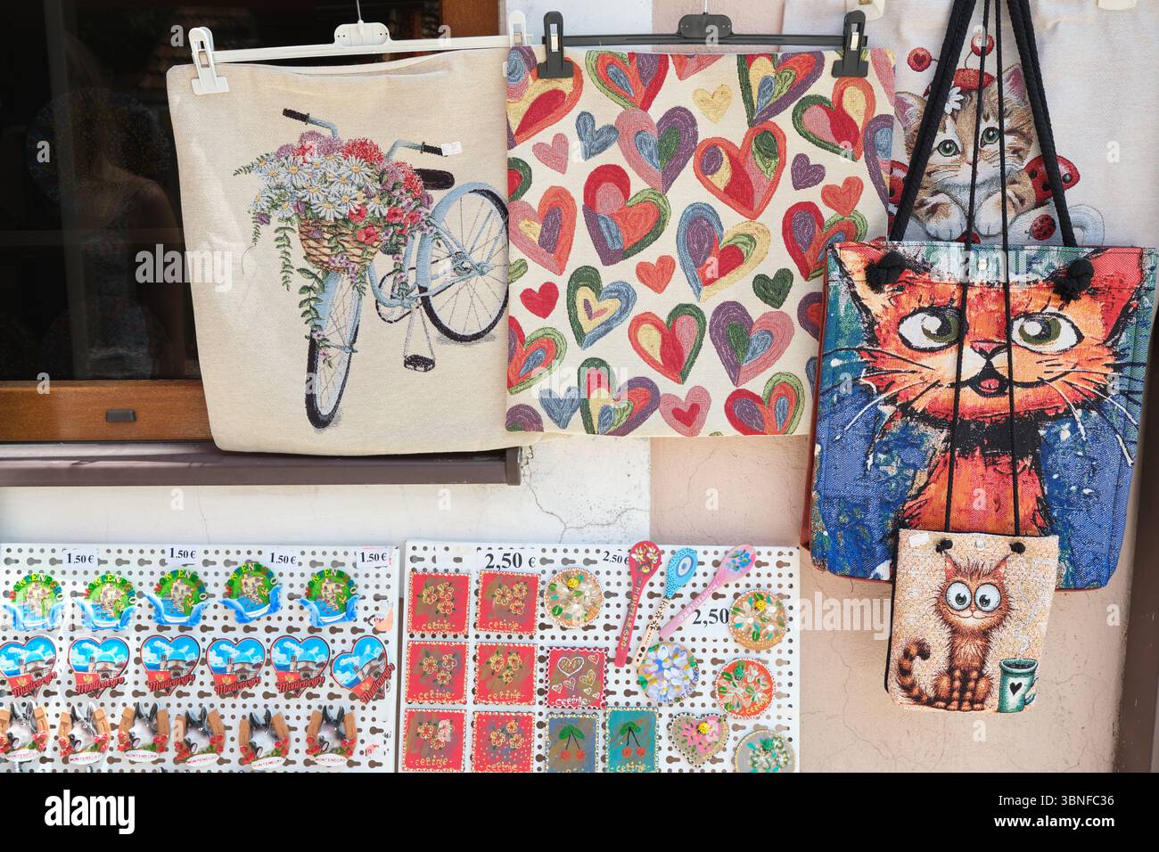 Cetinje, Montenegro - giugno 2025: Una collezione di borse tote colorate e magneti decorativi presentati all'esterno di un negozio locale in via Njegoševa Foto Stock
