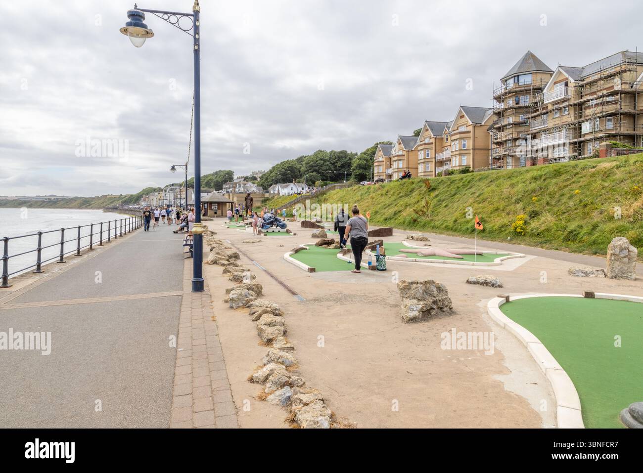 Le famiglie apprezzano il tradizionale minigolf sul mare al Filey, una classica località costiera britannica nello Yorkshire, popolare per le vacanze e il tempo libero. Vacanza in famiglia Foto Stock