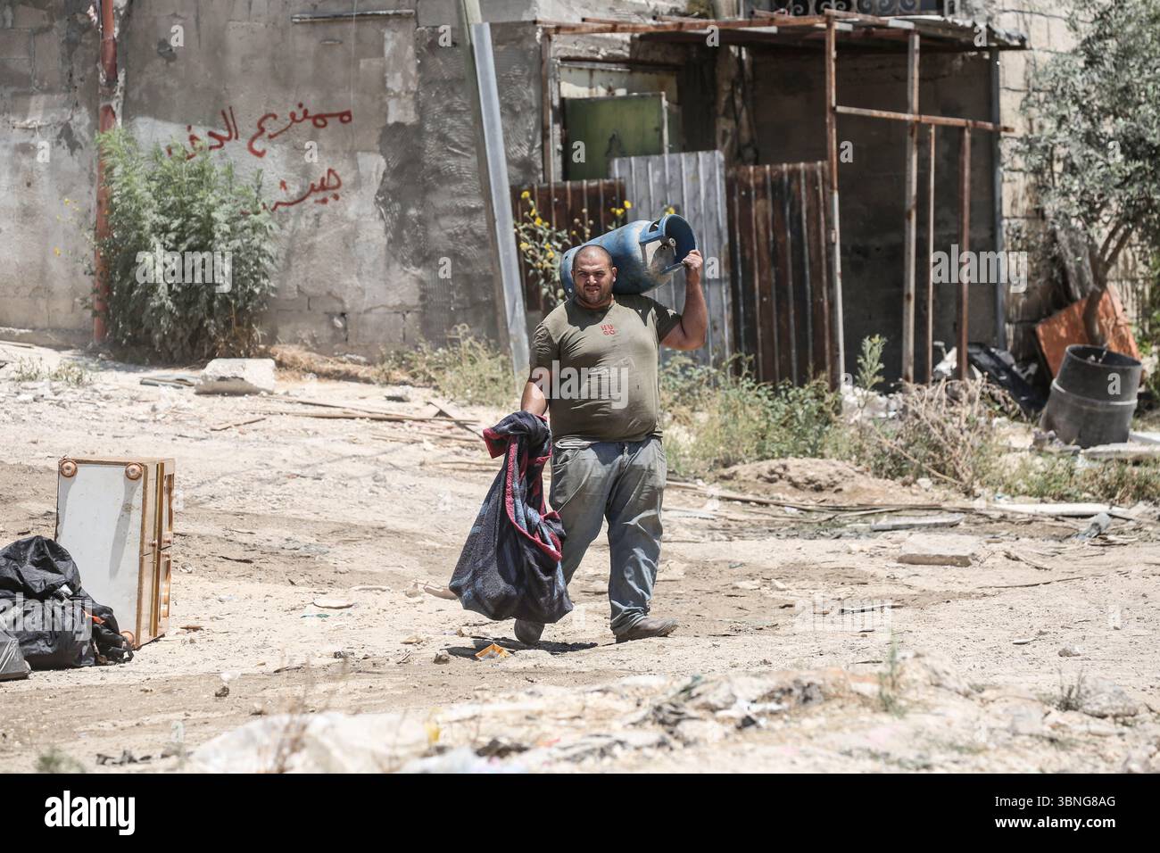 Tulkarm, Palestina. 2 luglio 2025. Un palestinese porta i propri effetti personali mentre fugge dal campo profughi di Tulkarm. Le forze israeliane hanno permesso ai residenti di recuperare i loro effetti personali dopo aver emesso avvisi di demolizione per diverse case, nel mezzo di un'offensiva durata mesi in Cisgiordania che ha allontanato circa 35.000 palestinesi dalle loro case nel campo profughi di Tulkarm. Credito: SOPA Images Limited/Alamy Live News Foto Stock