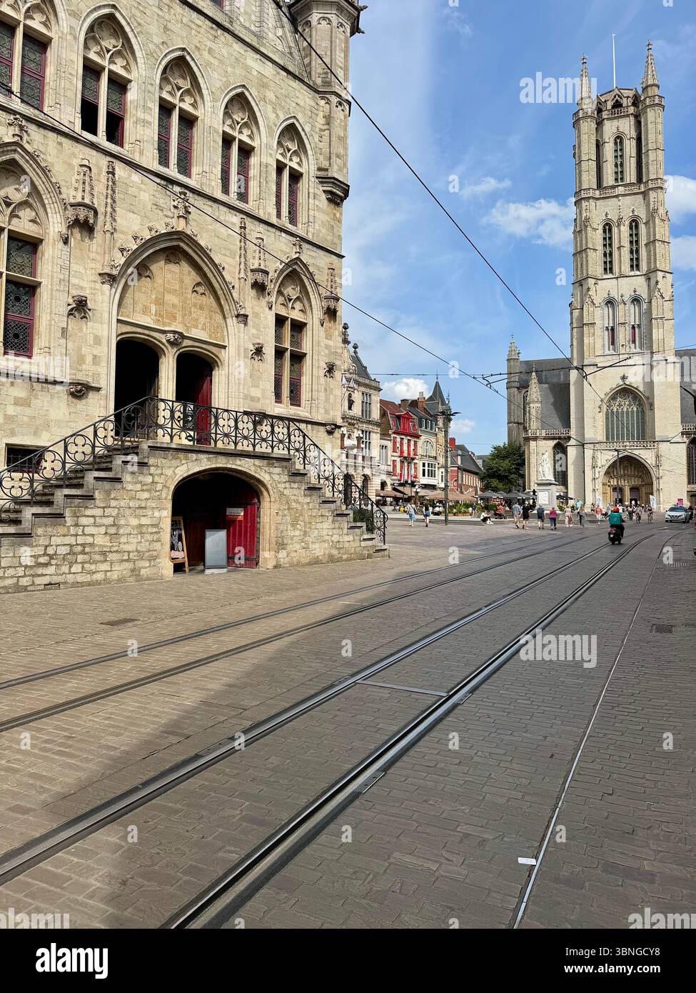 Belfry di Gand (Het Belfort van Gent) a sinistra e Cattedrale di San Bavone (Sint‑Baafskathedraal) a destra, con binari del tram in Kouter Square, GH Foto Stock