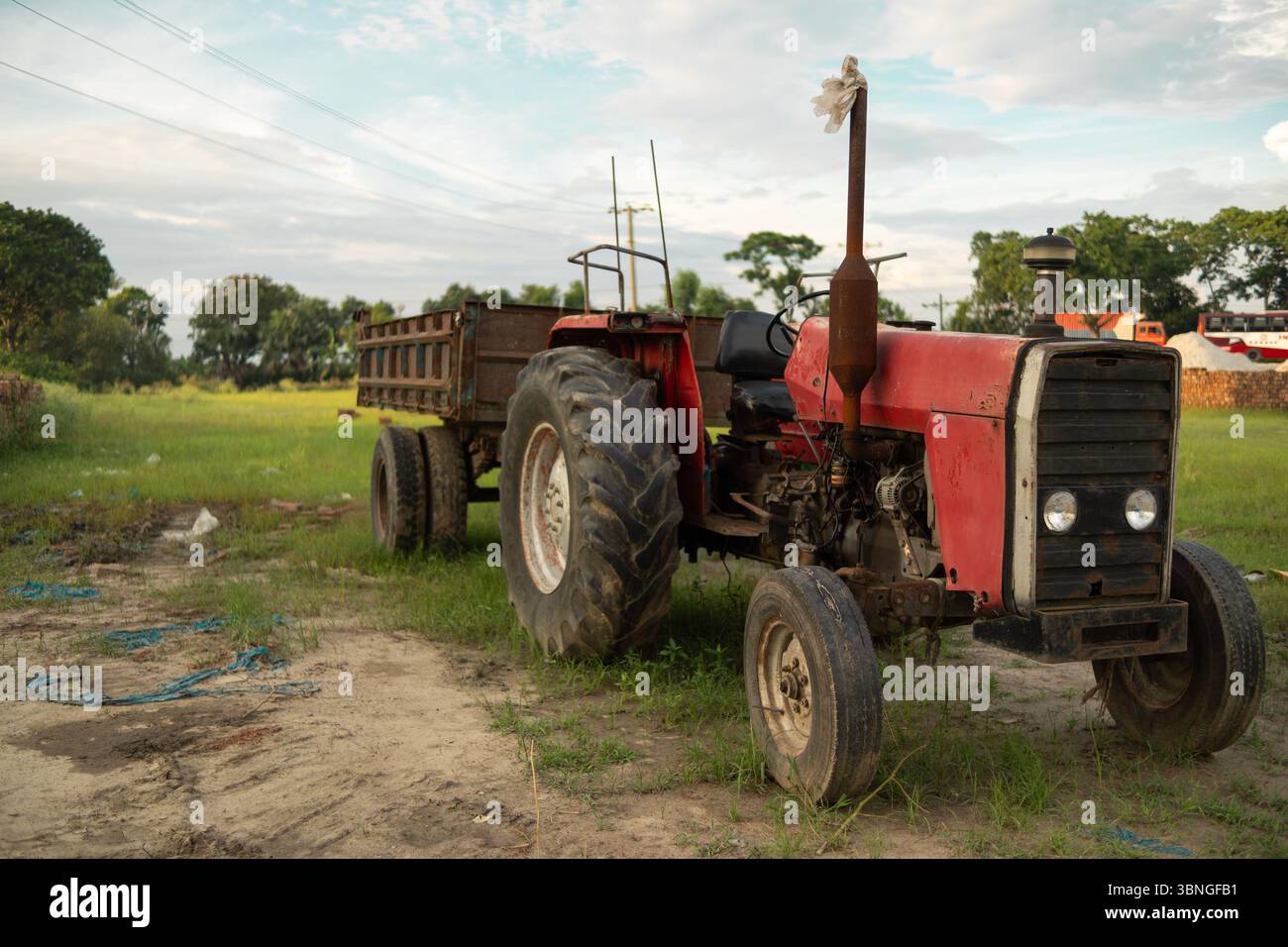 Un trattore rosso con rimorchio parcheggiato in un campo Foto Stock
