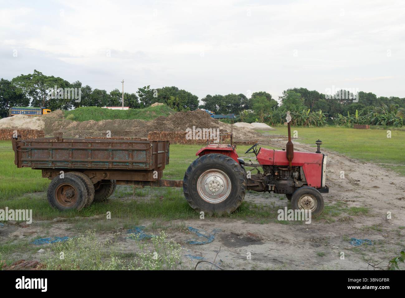 Un trattore rosso con rimorchio parcheggiato in un campo Foto Stock