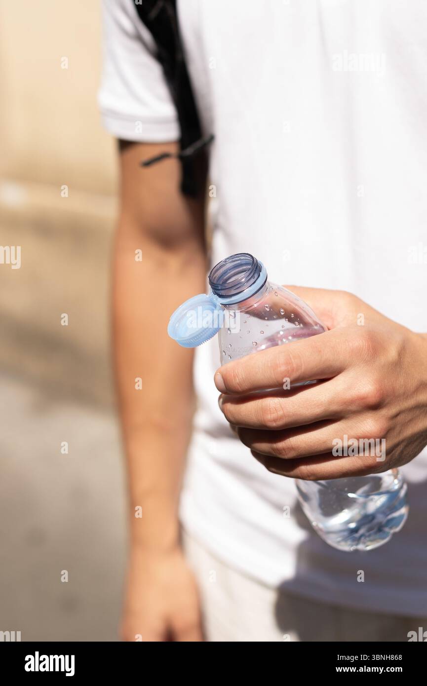 Tenere a mano una bottiglia d'acqua rinfrescante in una calda giornata a Parigi. Idratazione essenziale durante un'onda di calore. Foto Stock