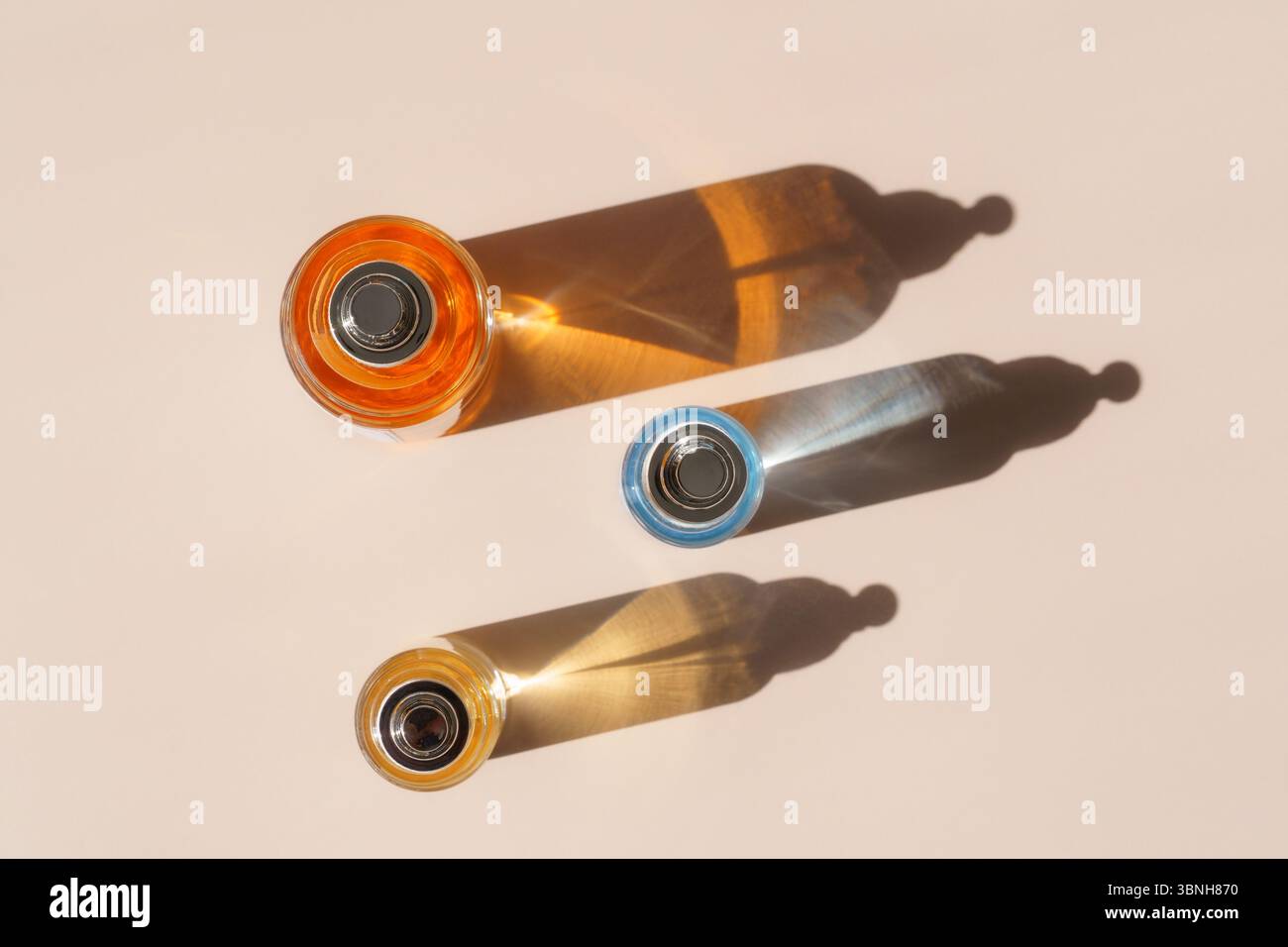 Bottiglie di profumo colorate con luce rifrangente e ombre dure dall'alto Foto Stock