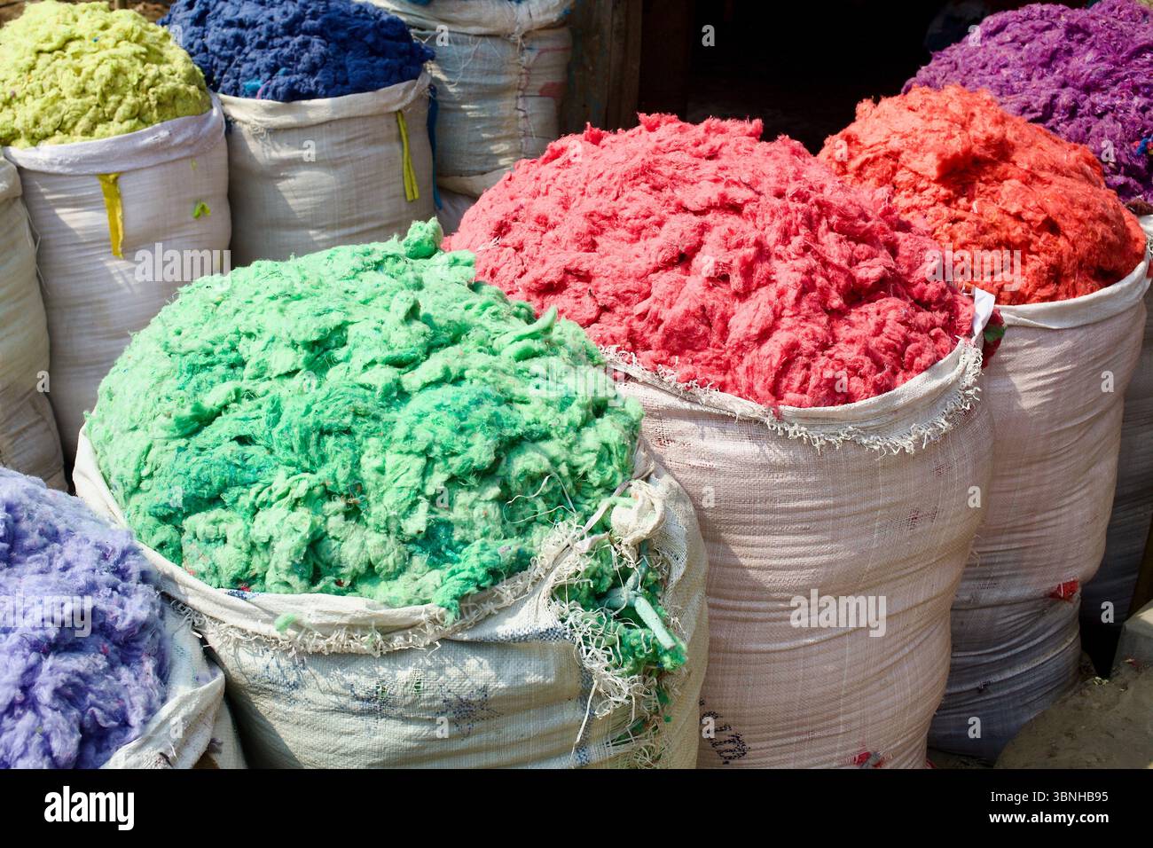Fibre tessili colorate brillantemente in sacchi sfusi, Kurigram, Bangladesh, in attesa di lavorazione o rivendita nell'economia informale del riciclaggio. Foto Stock