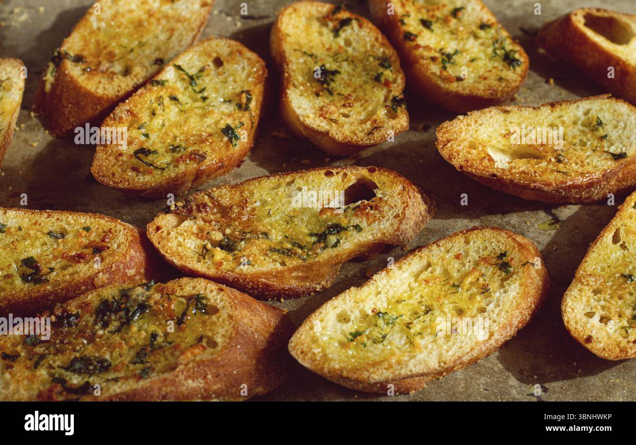 Baguette tostate, cotte nel forno, con burro all'aglio ed erbe aromatiche, fatte in casa, su un piatto, vista dall'alto Foto Stock