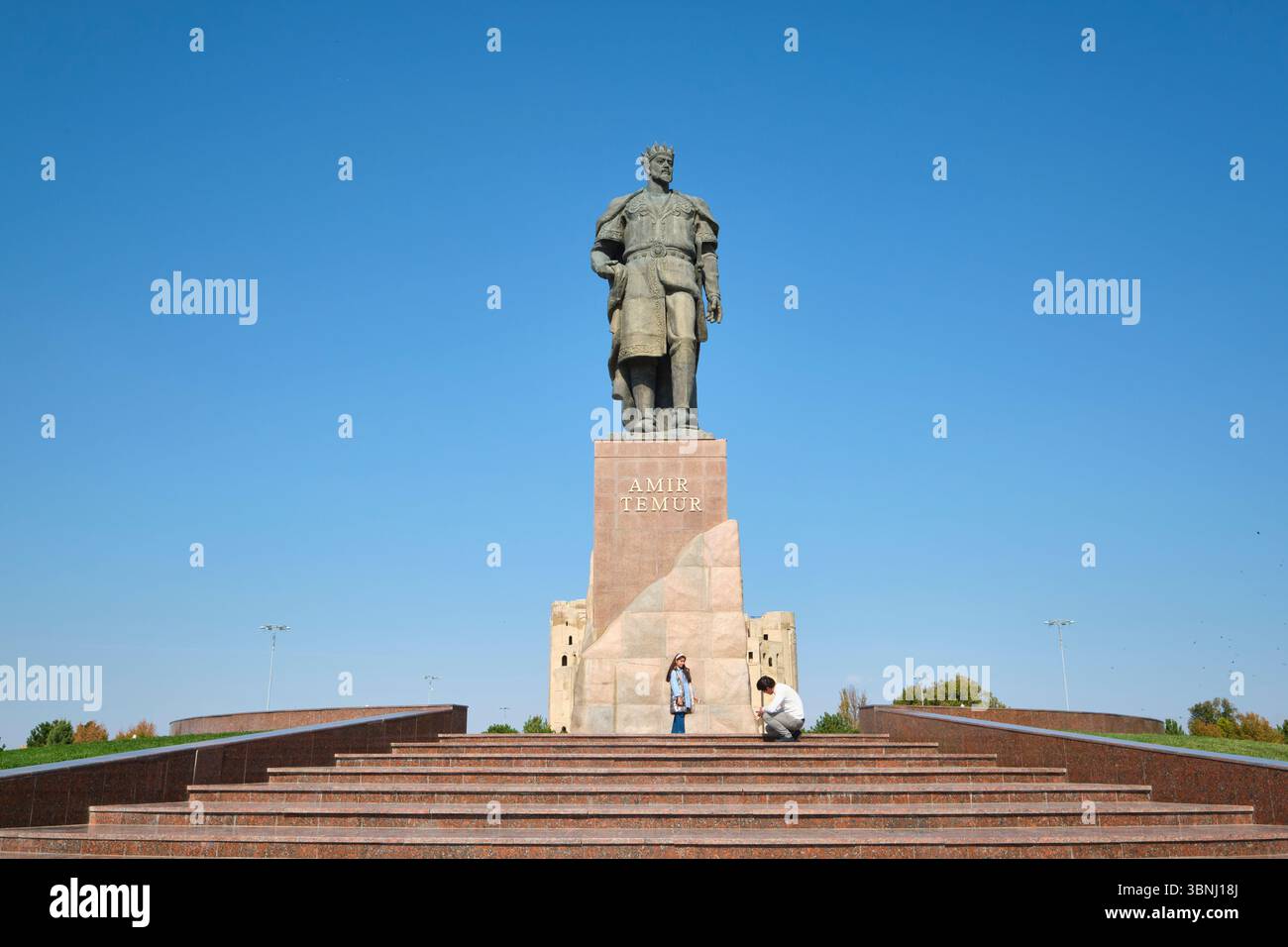 Una tipica scena di una coppia che posa per le foto davanti . Presso l'enorme scultura di Amir Timur, statua del leader a Shahrisabz, Uzbekistan. Foto Stock
