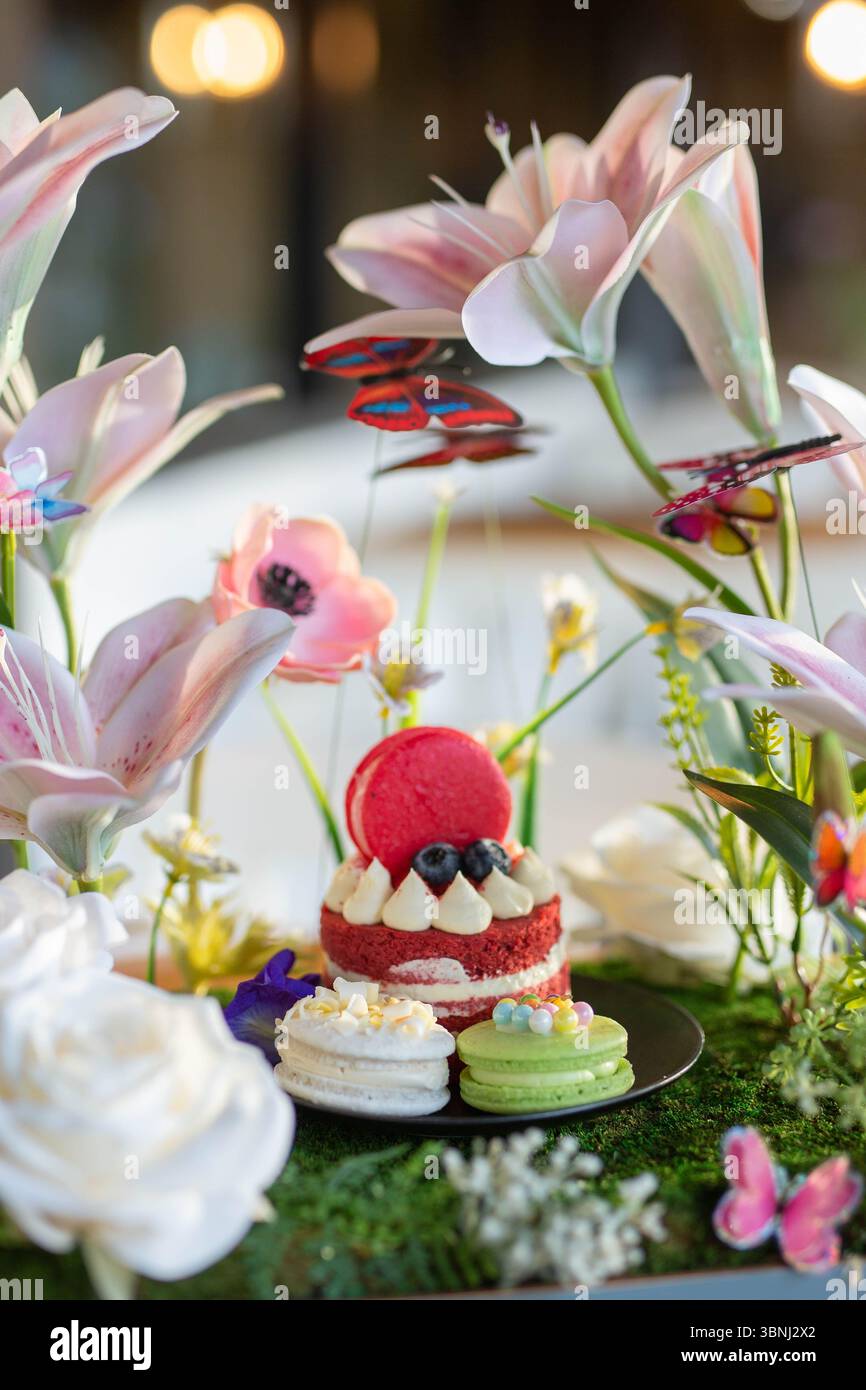 Una deliziosa fetta di torta di velluto rosso con strati cremosi di crema di formaggio liscio, splendidamente guarnita con fiori a margherita viola. Foto Stock