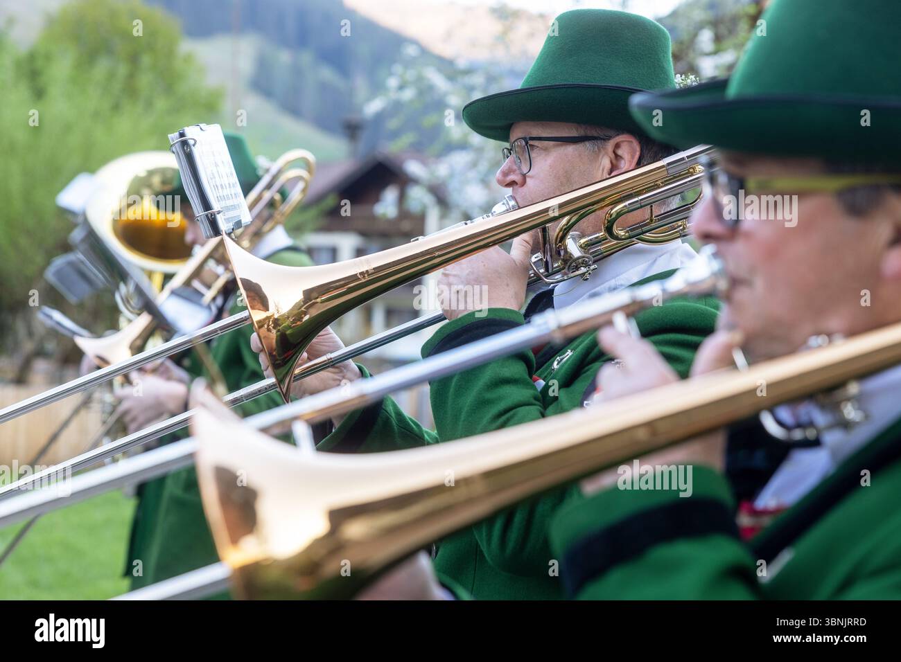 I musicisti della cappella nazionale suonano i loro strumenti in una serena giornata primaverile in un villaggio austriaco, circondato da lussureggiante vegetazione e traditiona Foto Stock