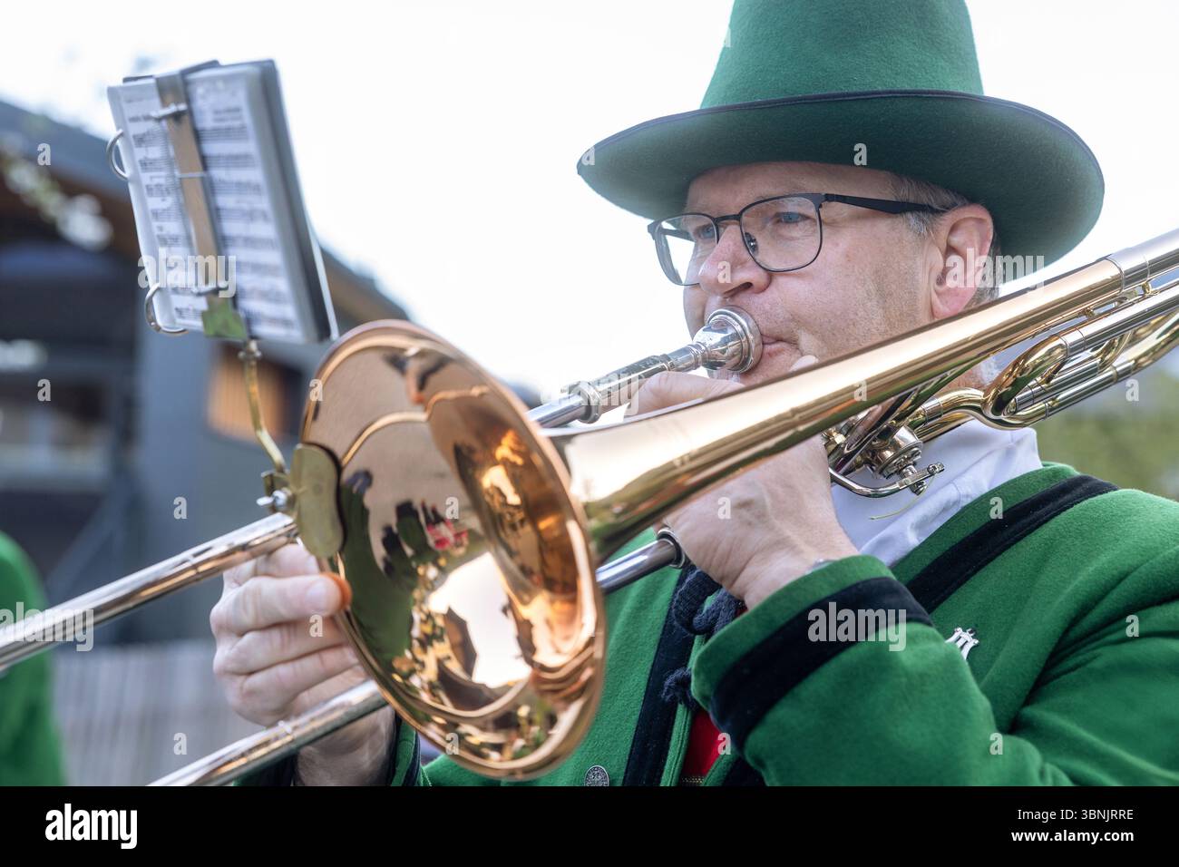 I musicisti della cappella nazionale si esibiscono all'aperto in una luminosa giornata primaverile in un villaggio austriaco, indossando un tradizionale abbigliamento verde, aggiungendo un ric culturale Foto Stock