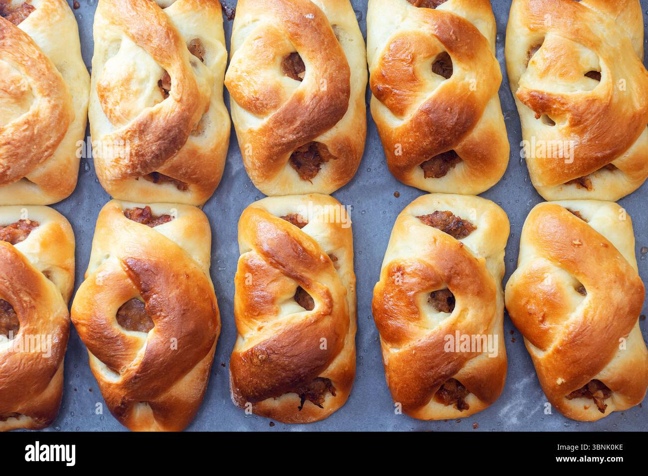 Un vassoio di panini dolci appena sfornati, ripieni di deliziose conserve di frutta, che mostrano un'atmosfera rustica e accogliente da cucina. Perfetto per una casa calda Foto Stock